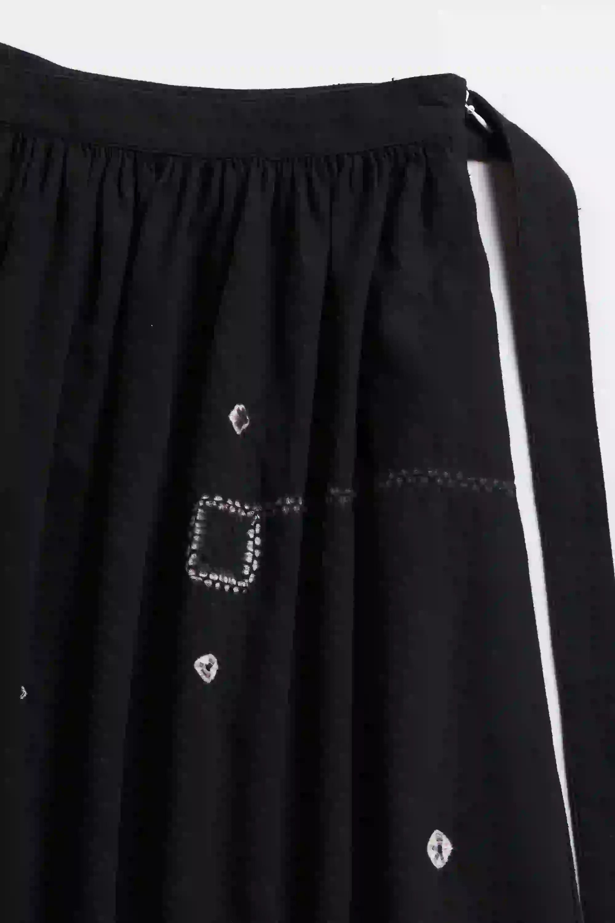 Black skirt with decorative stitching and embellishments on a white background