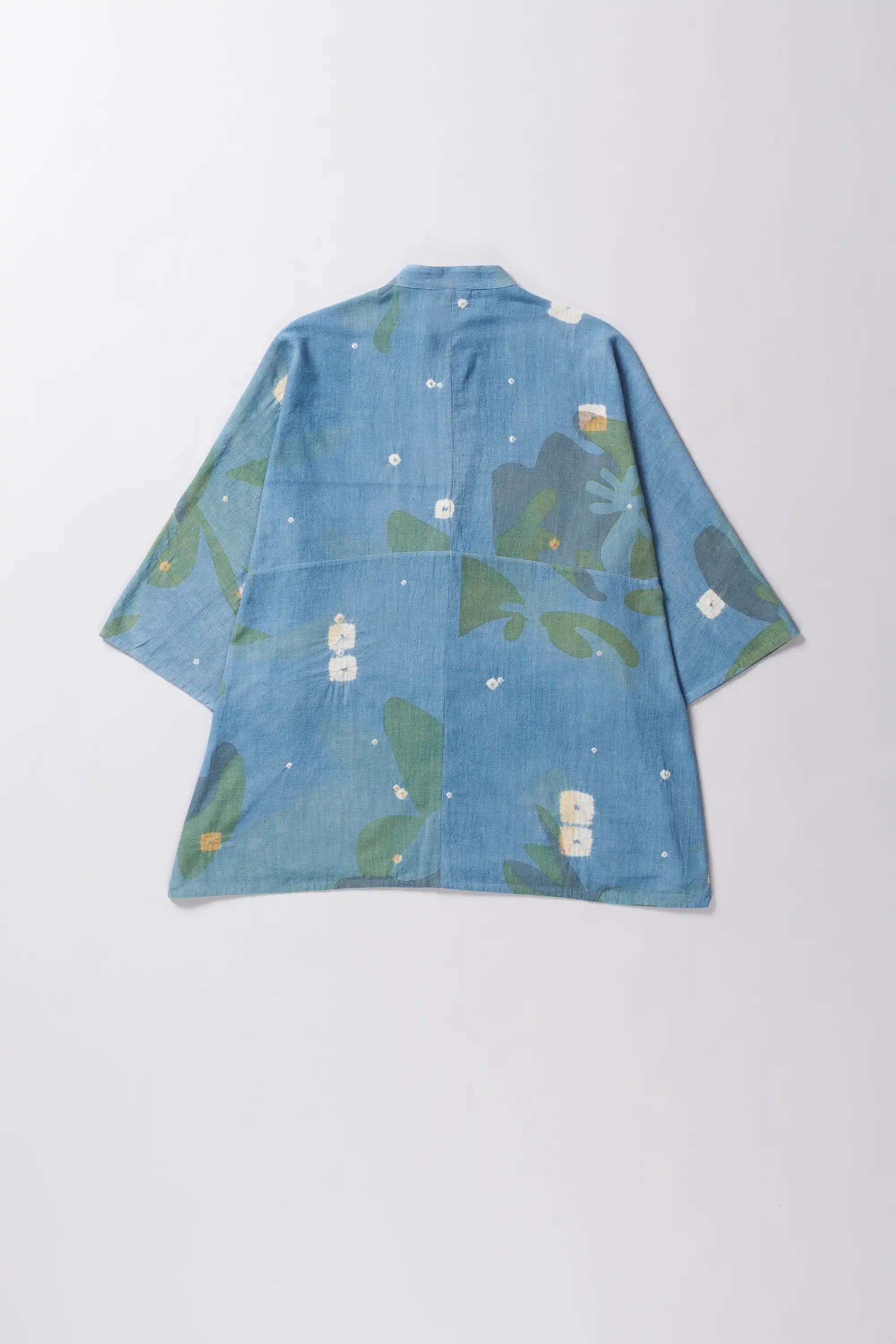 Blue denim shirt with green floral pattern on a white background