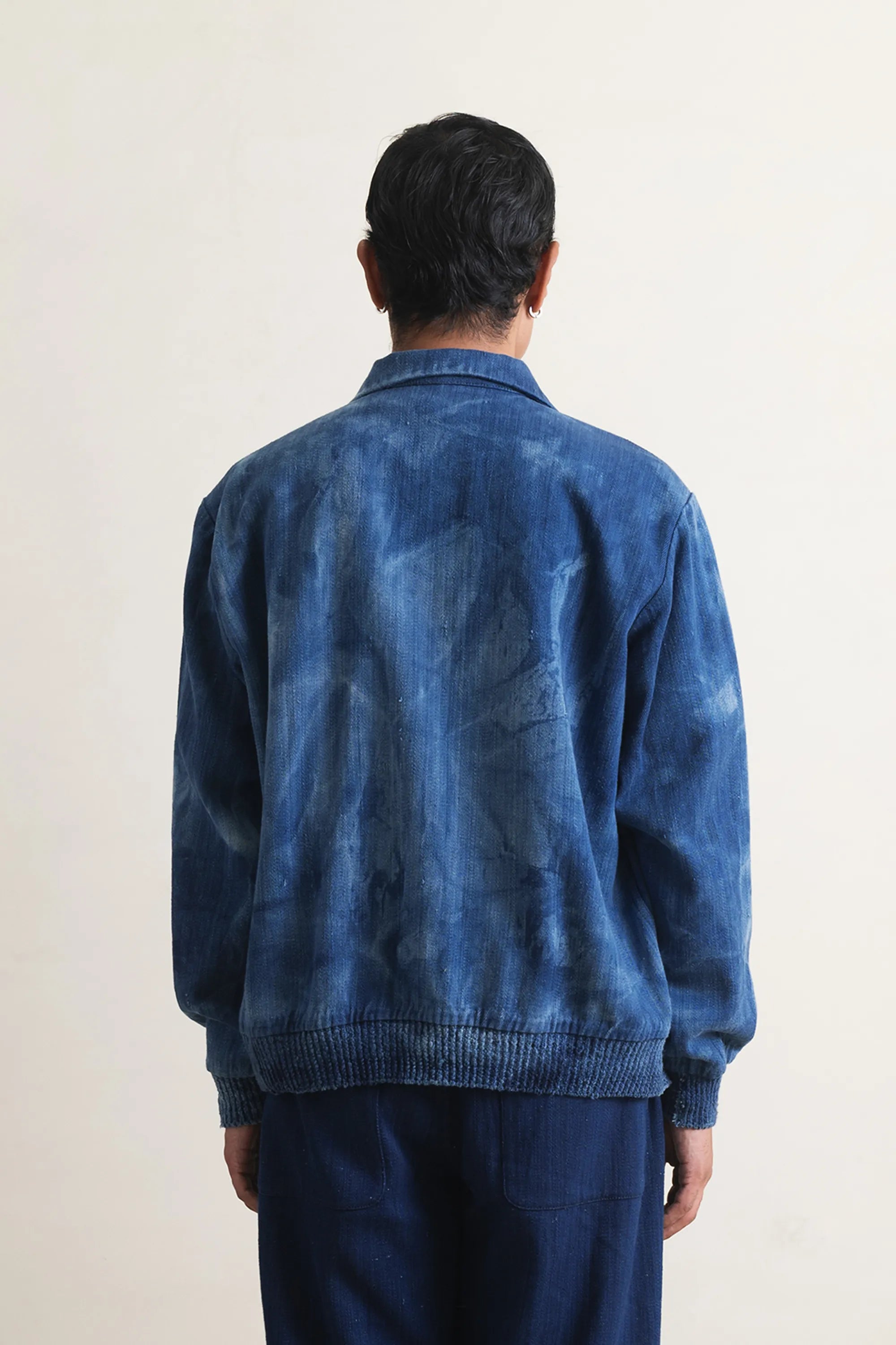Back shot of a person wearing a blue denim jacket with a light grey background