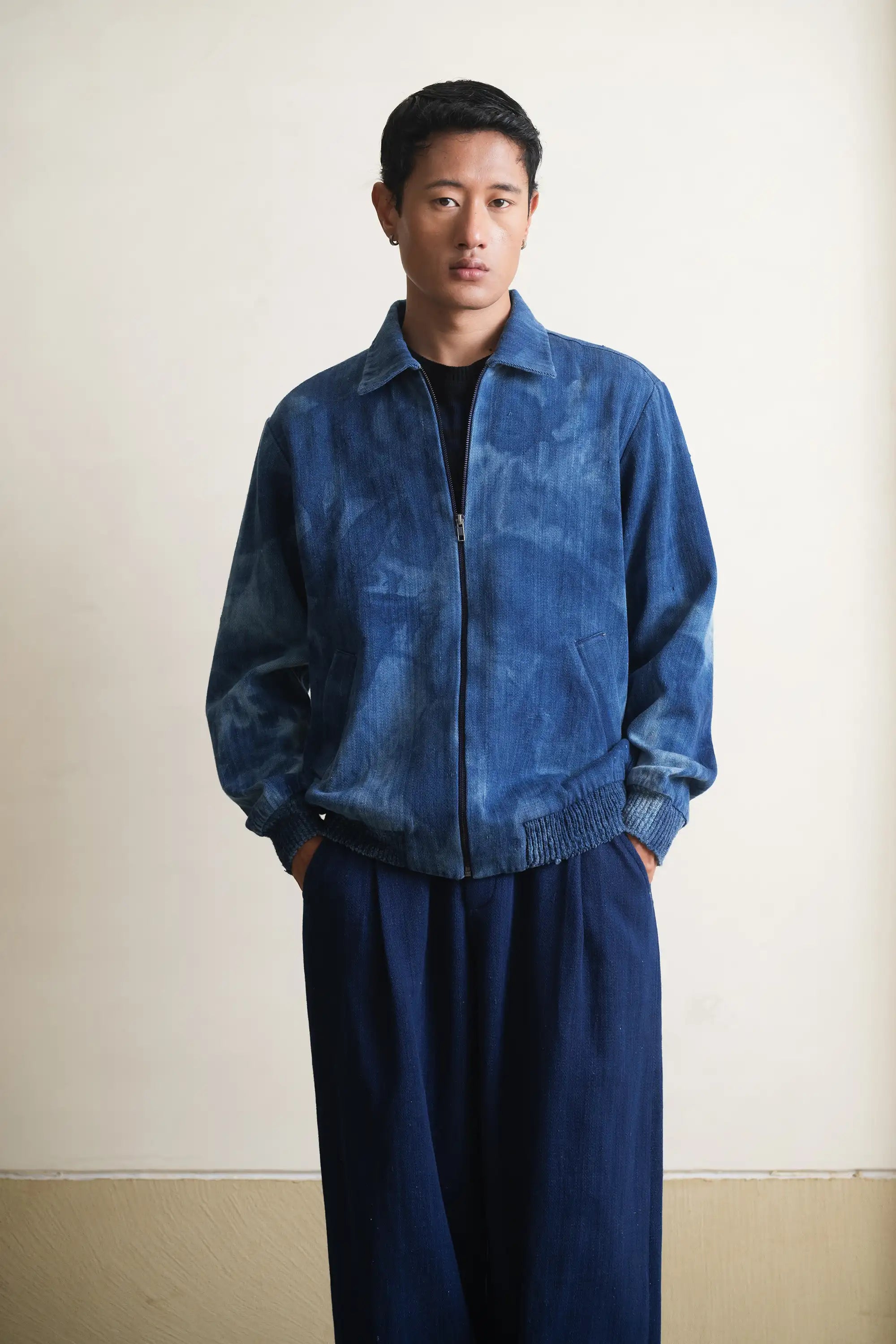 Man wearing a blue jacket and pants against a plain background