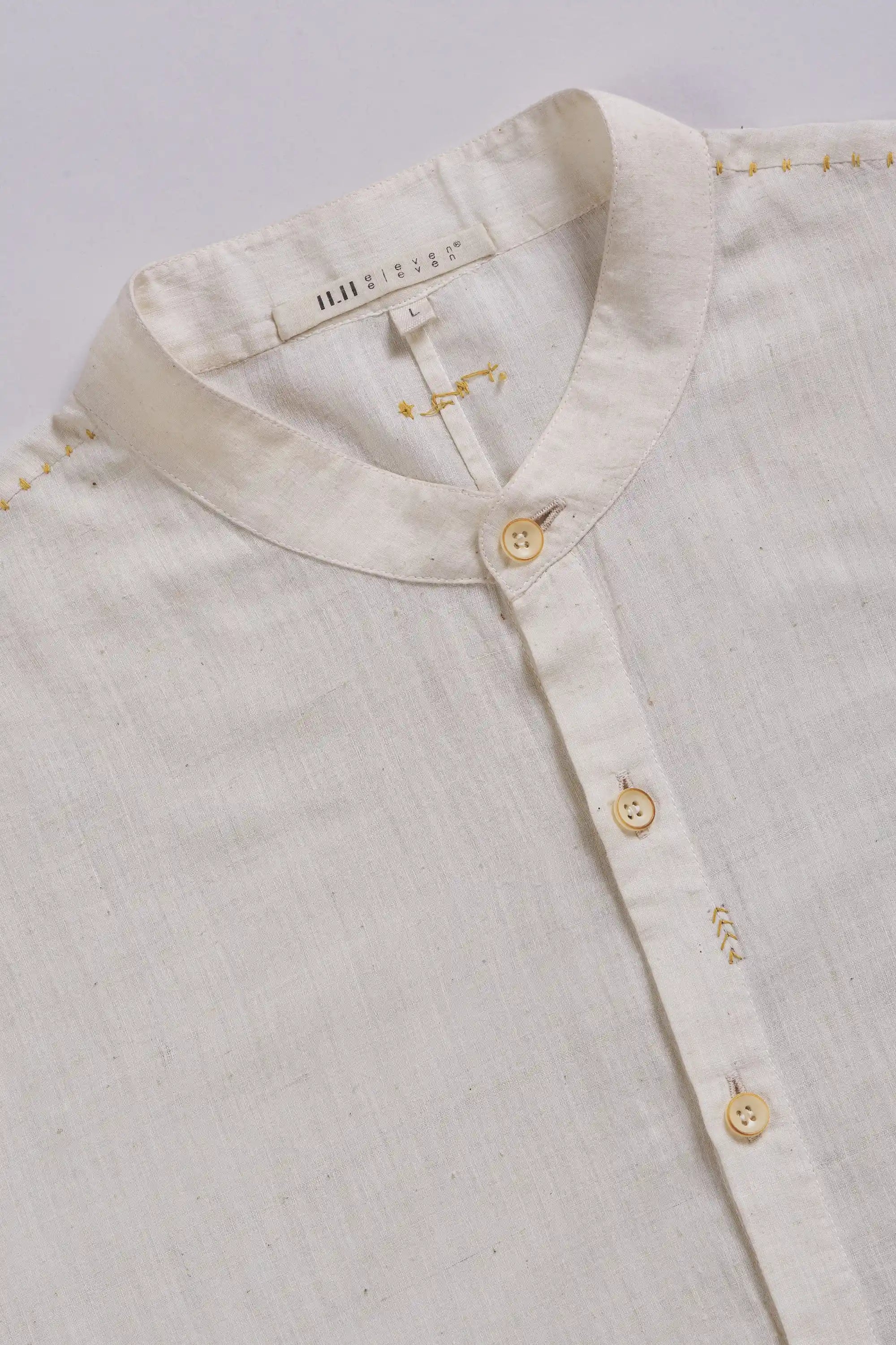 Close-up of a light-colored shirt with buttons on a light grey background