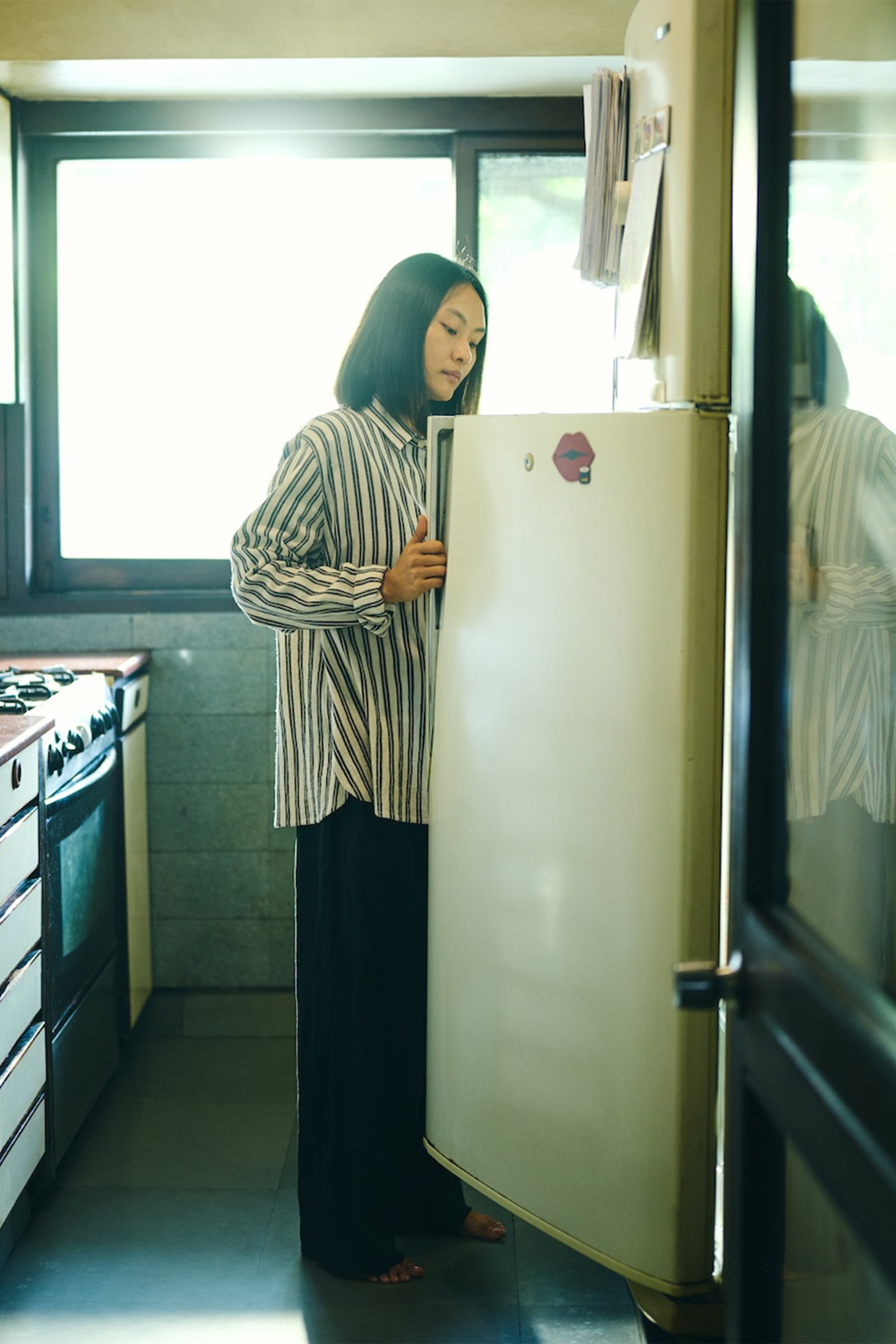 A woman wearing medium indigo cotton yarn dyed stripes shirt
