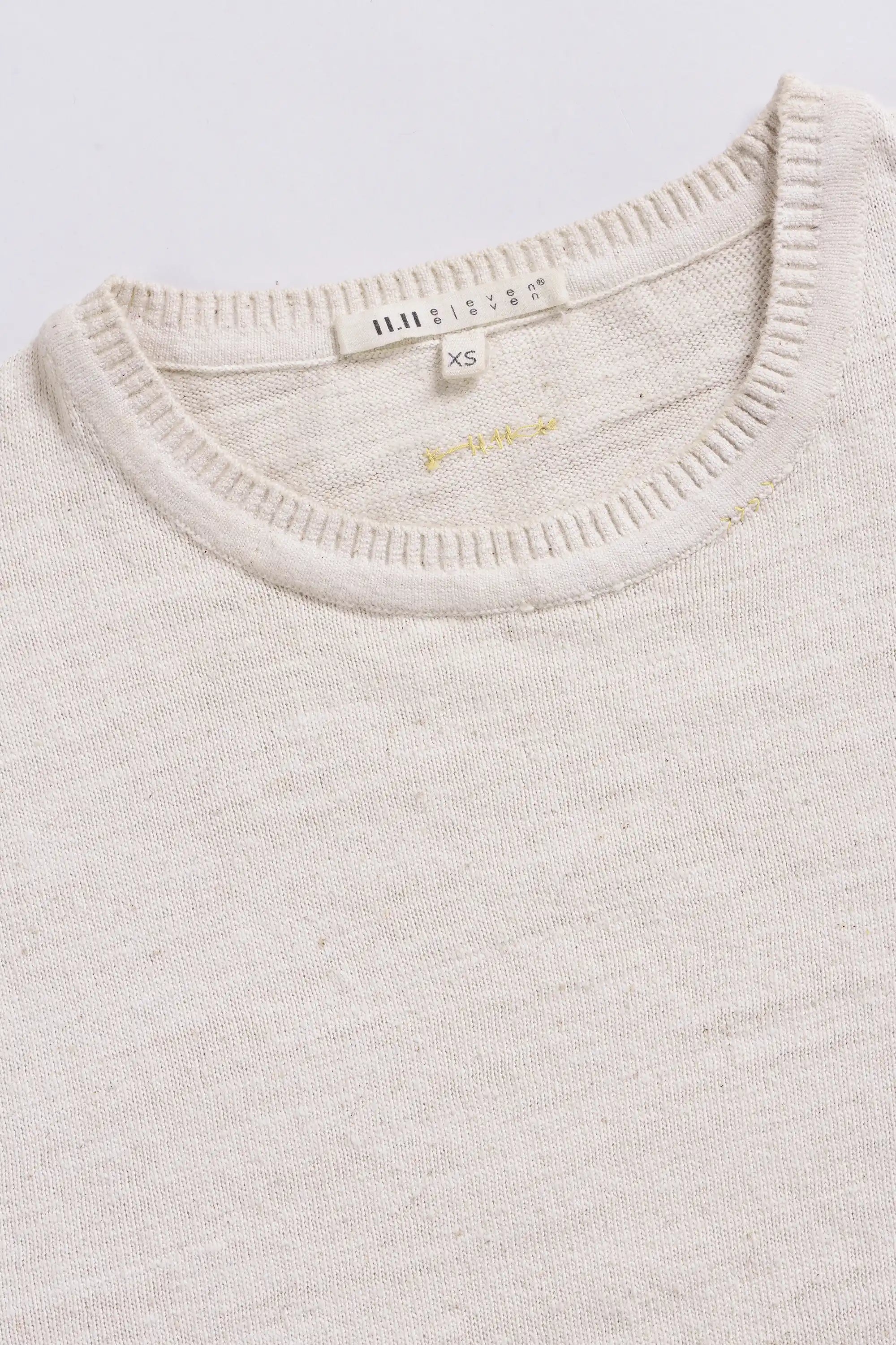 Close-up of a sweater with brand label on a light grey background