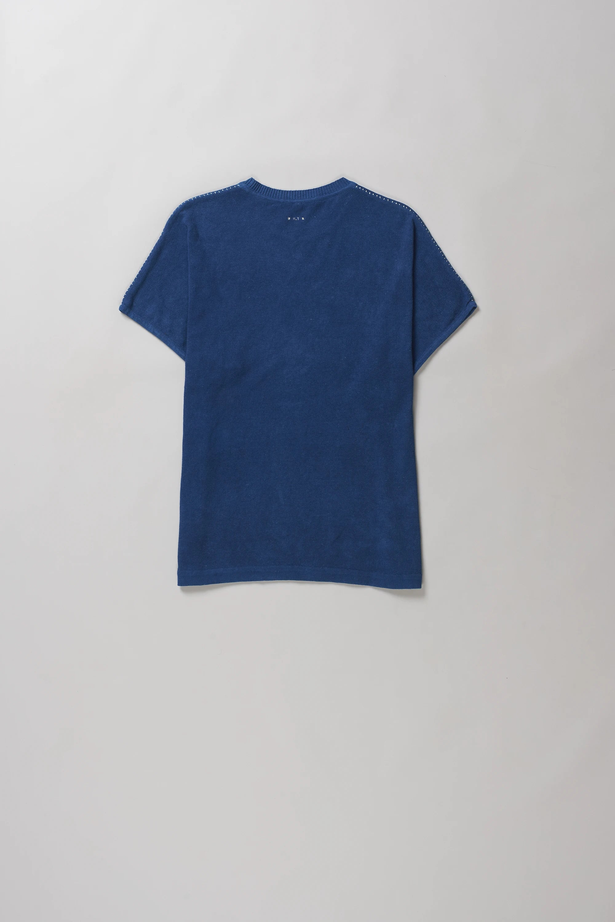 Back shot of solid medium indigo short-sleeve crewneck t-shirt laid flat against a light grey background.