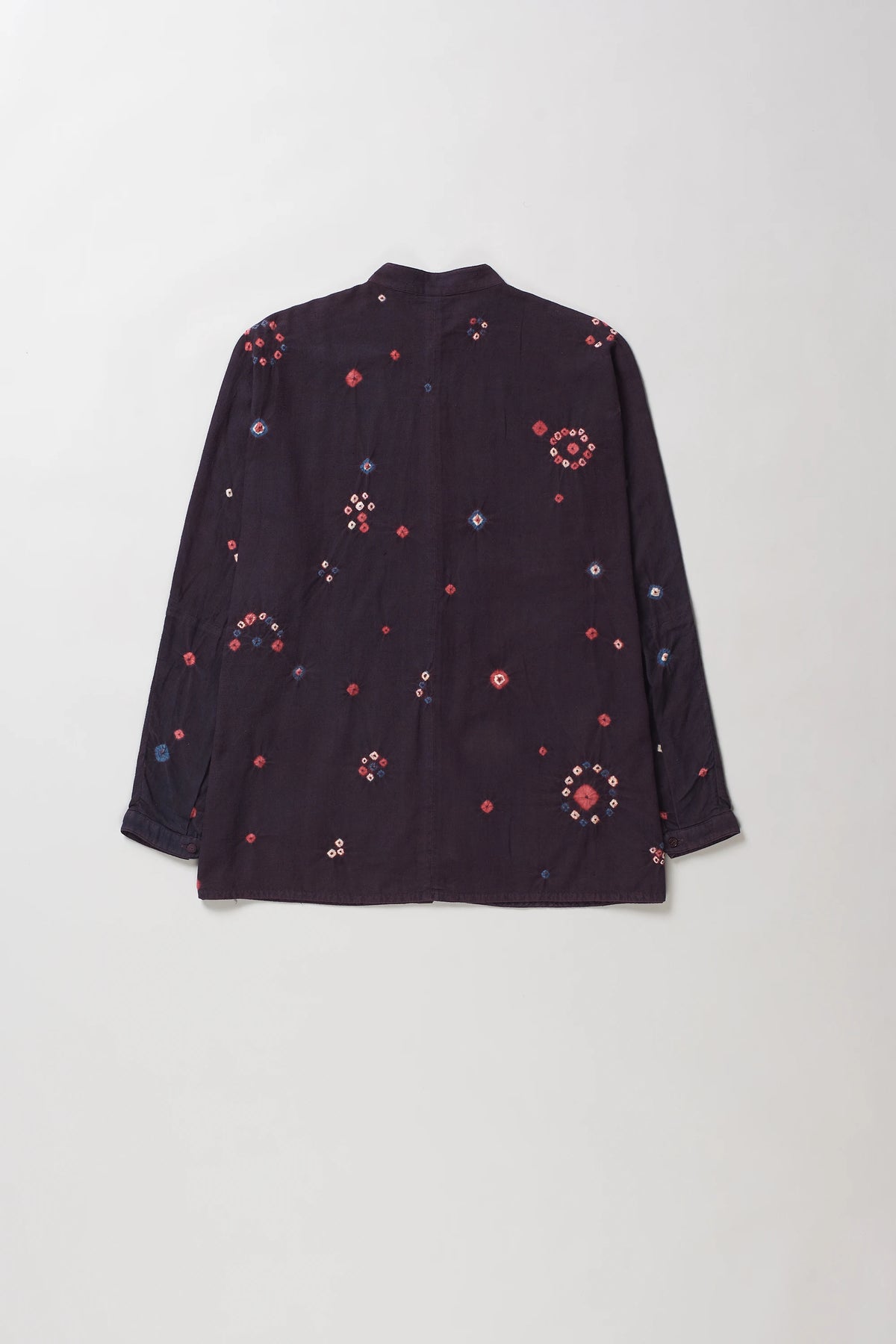 Back shot of purple red long-sleeve button-up shirt with colorful bandhani floral motifs, shown flat against a light grey background.