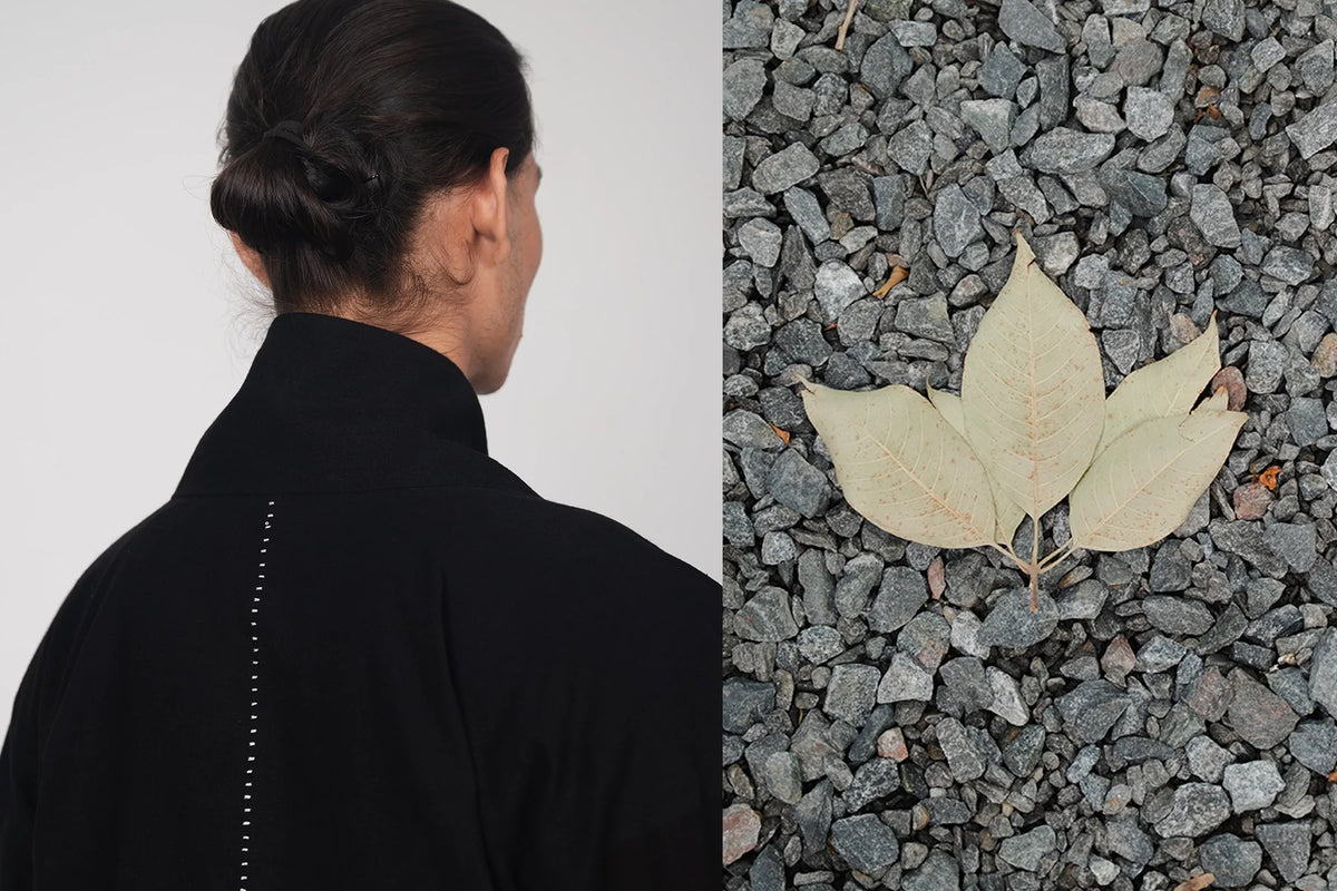 A man wearing a black jacket with a white background and a leaf on gray gravel.