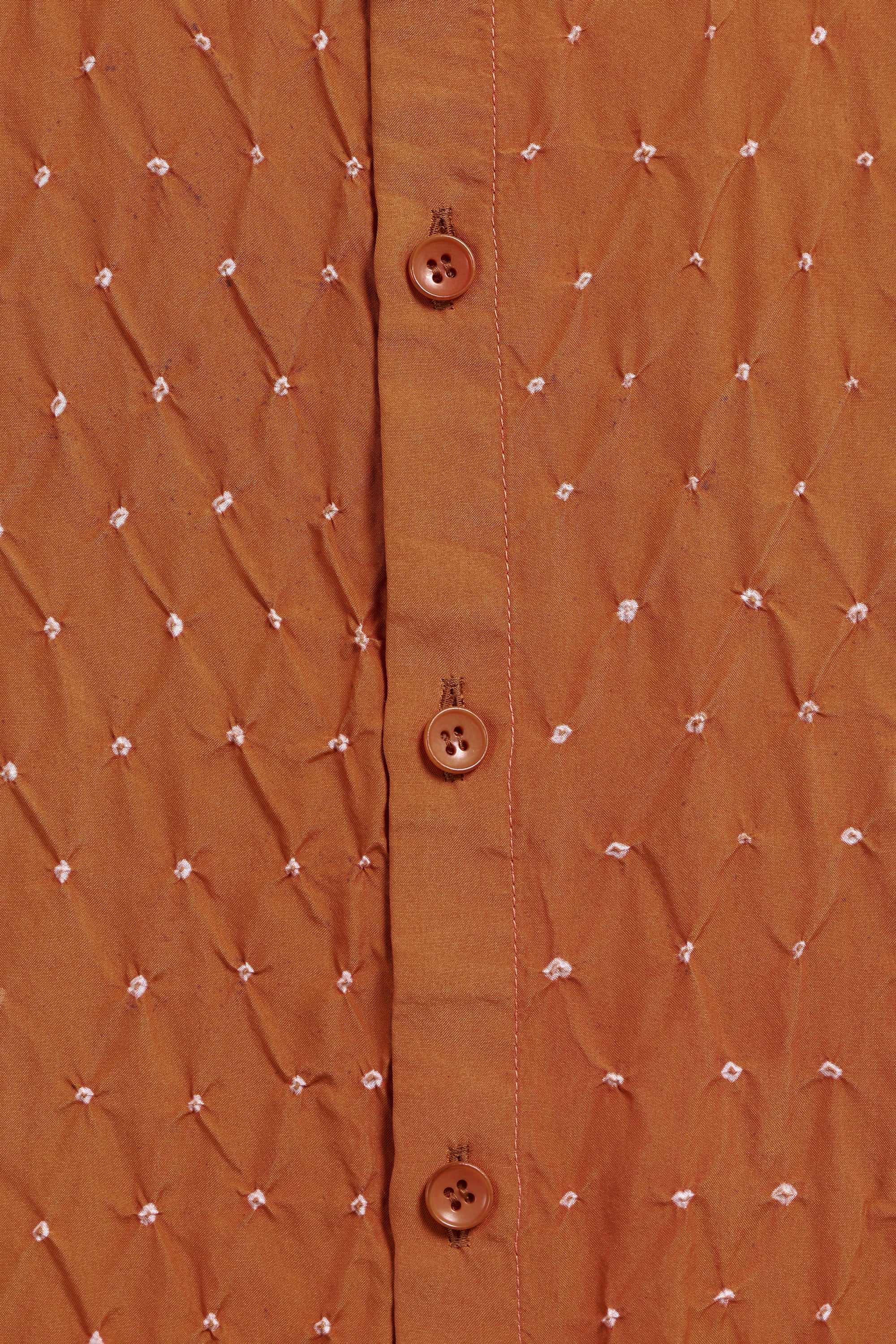 Close-up of a brown textured shirt with button