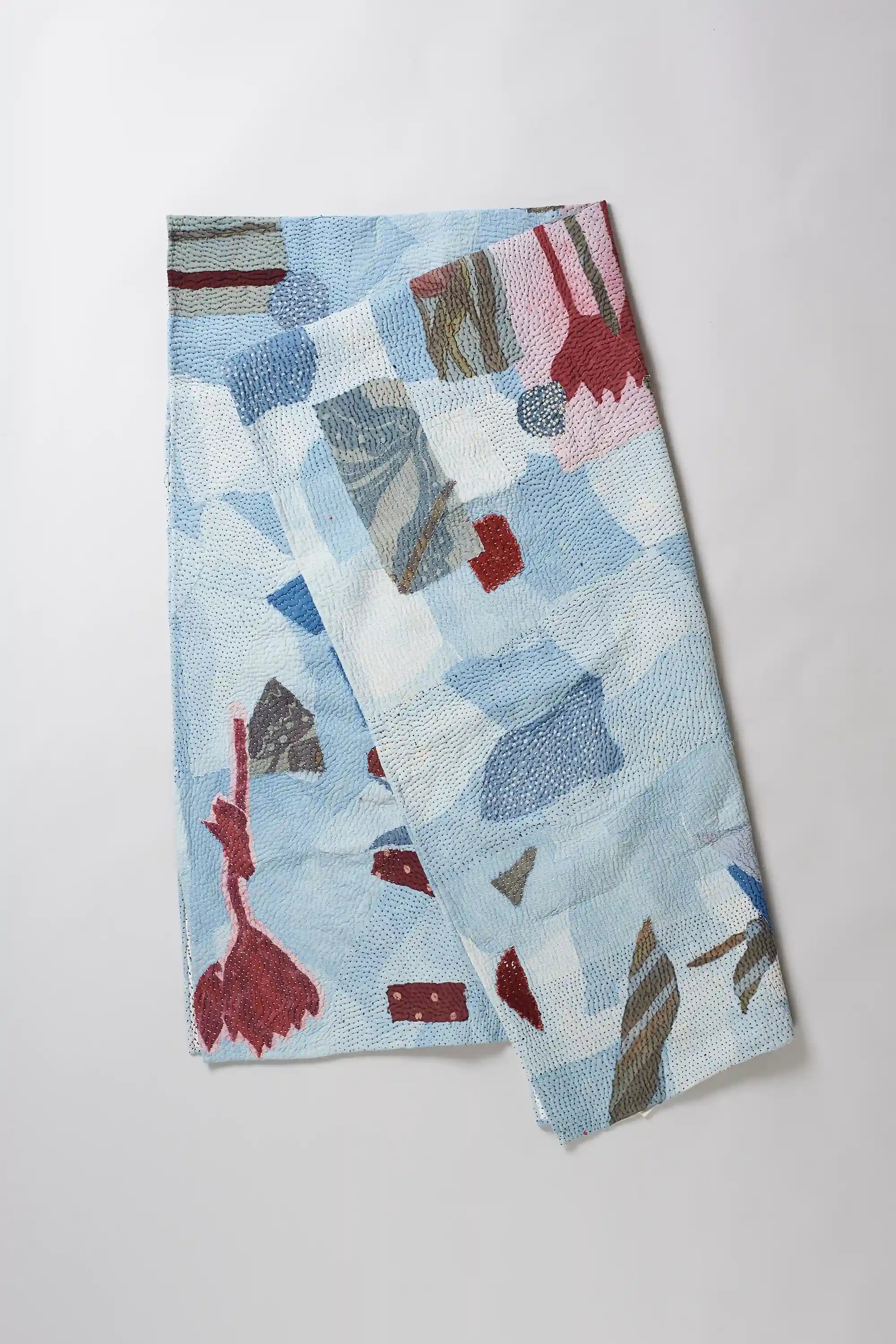 Folded patchwork quilt on light grey background