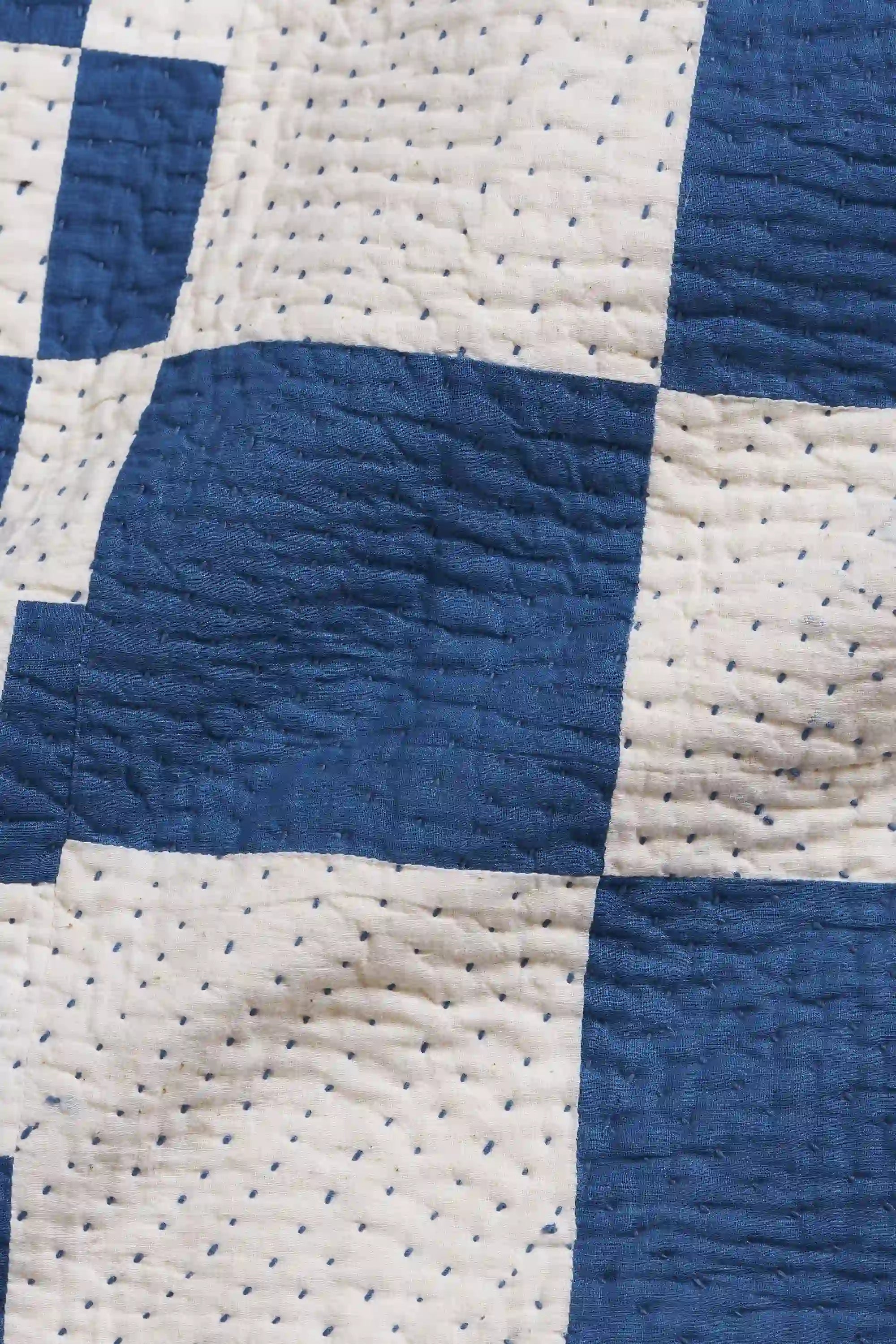 Close-up of a blue and white checkered quilt with visible stitching.