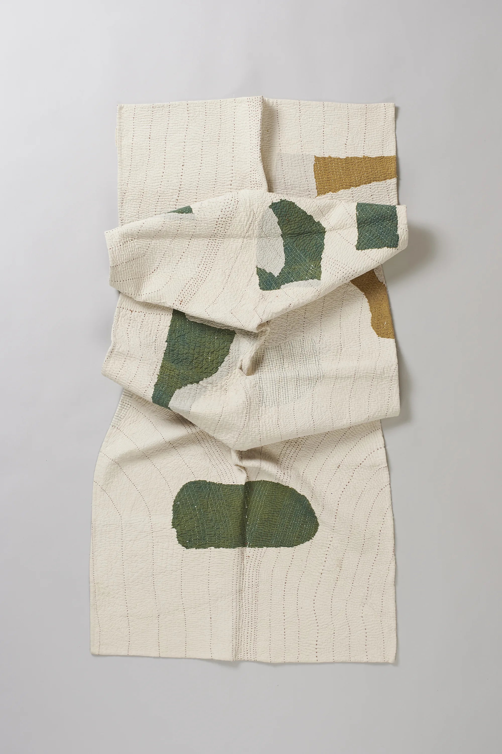 Ecru cotton quilt on a light grey background