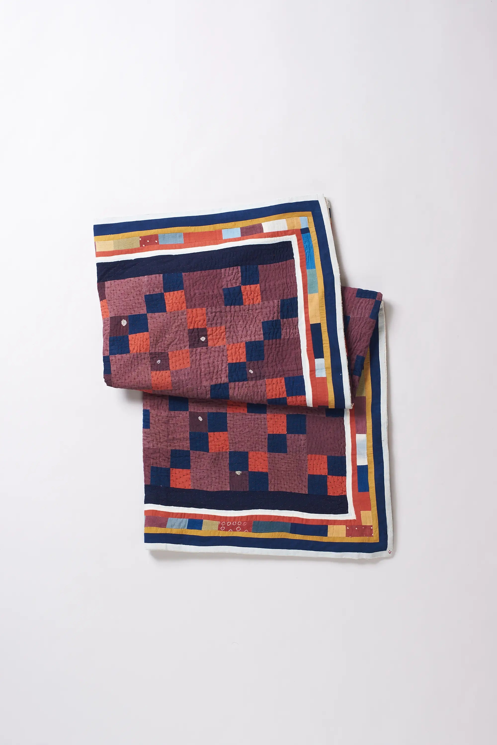 Colorful patterned quilt on a white background