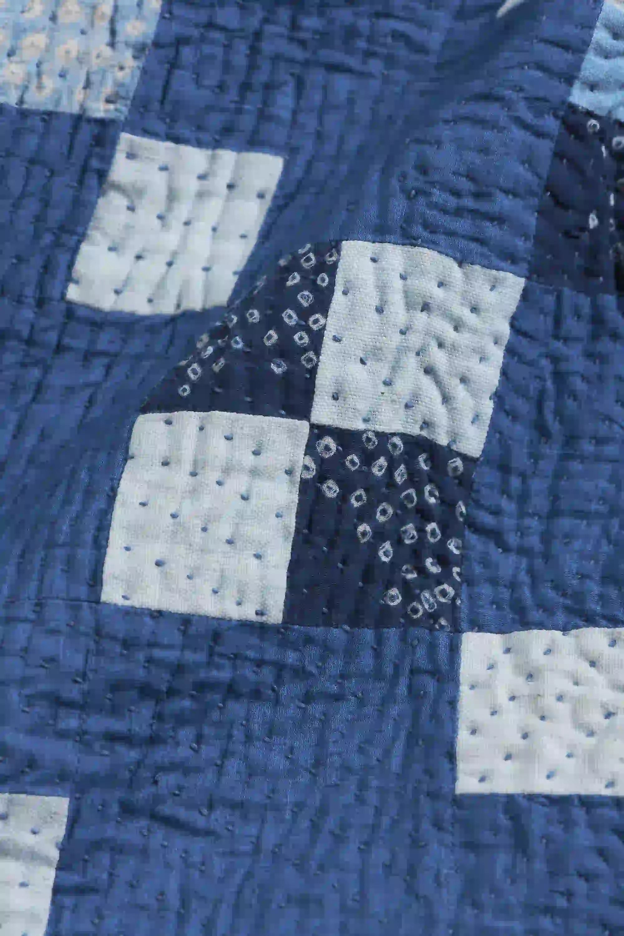 Close-up of a blue and white quilt with a diamond pattern