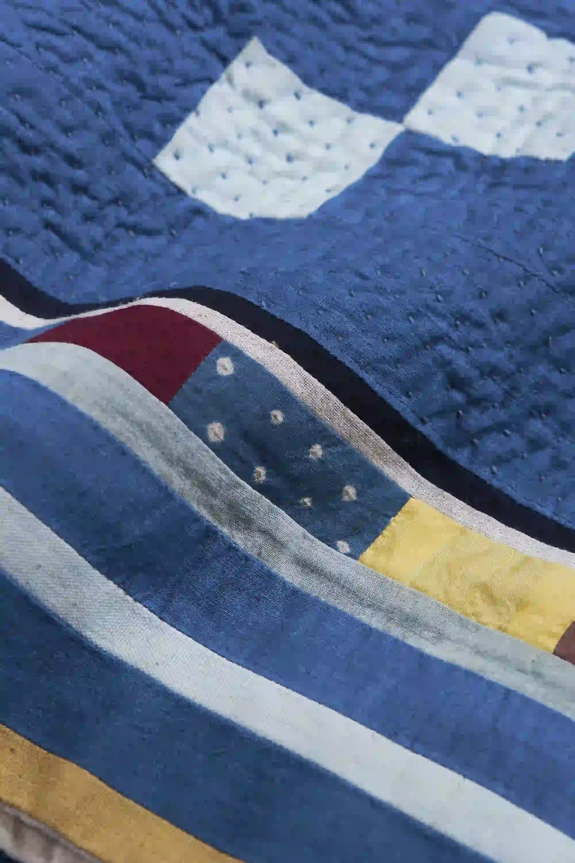 Close-up of a quilt with blue, white, red, and yellow patterns