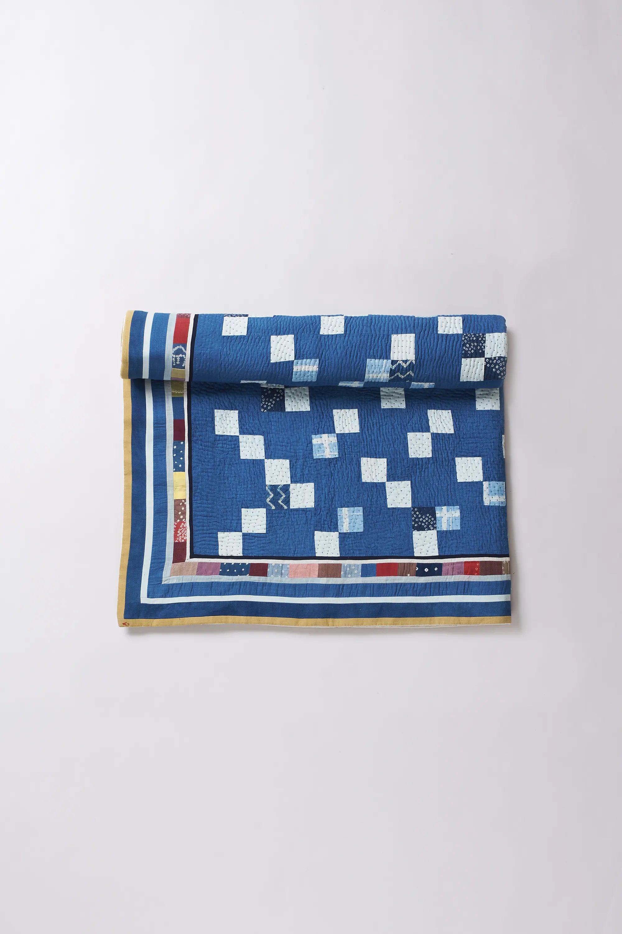 Folded quilt with blue and white checkered pattern on a light gray background