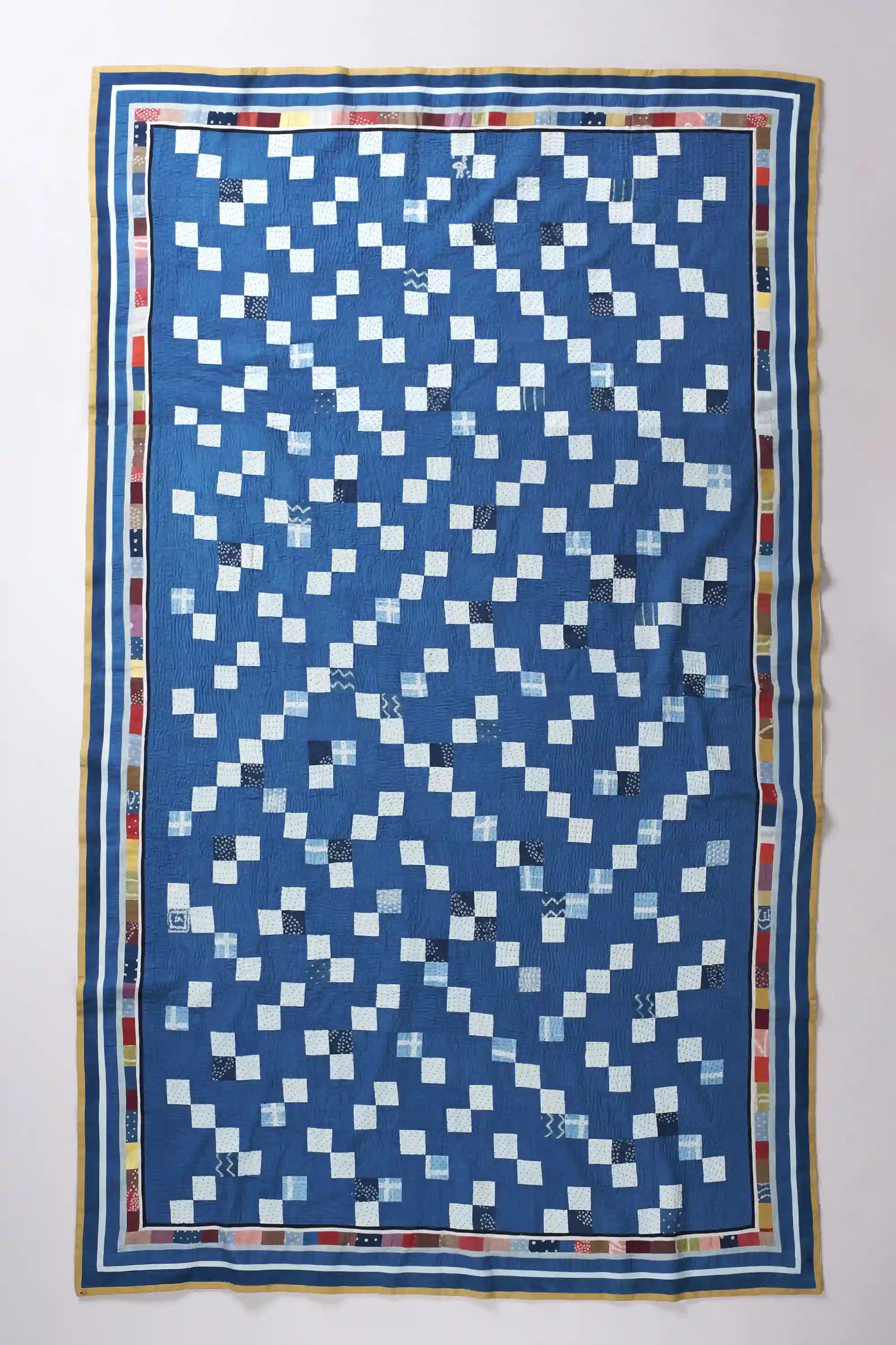 Blue and white diamond patterned quilt on a plain background