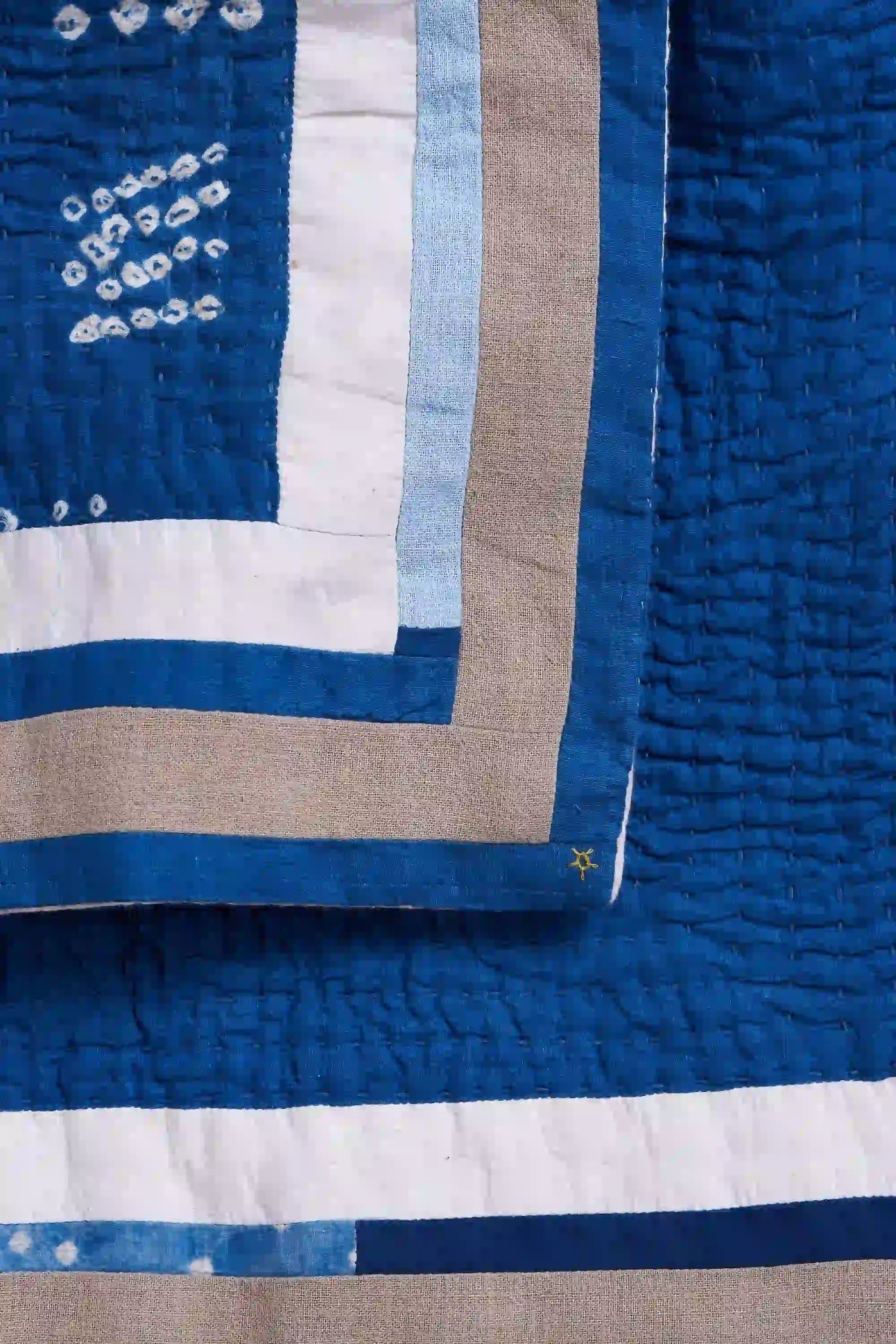 Close-up of a quilt with blue, white, and beige stripes.