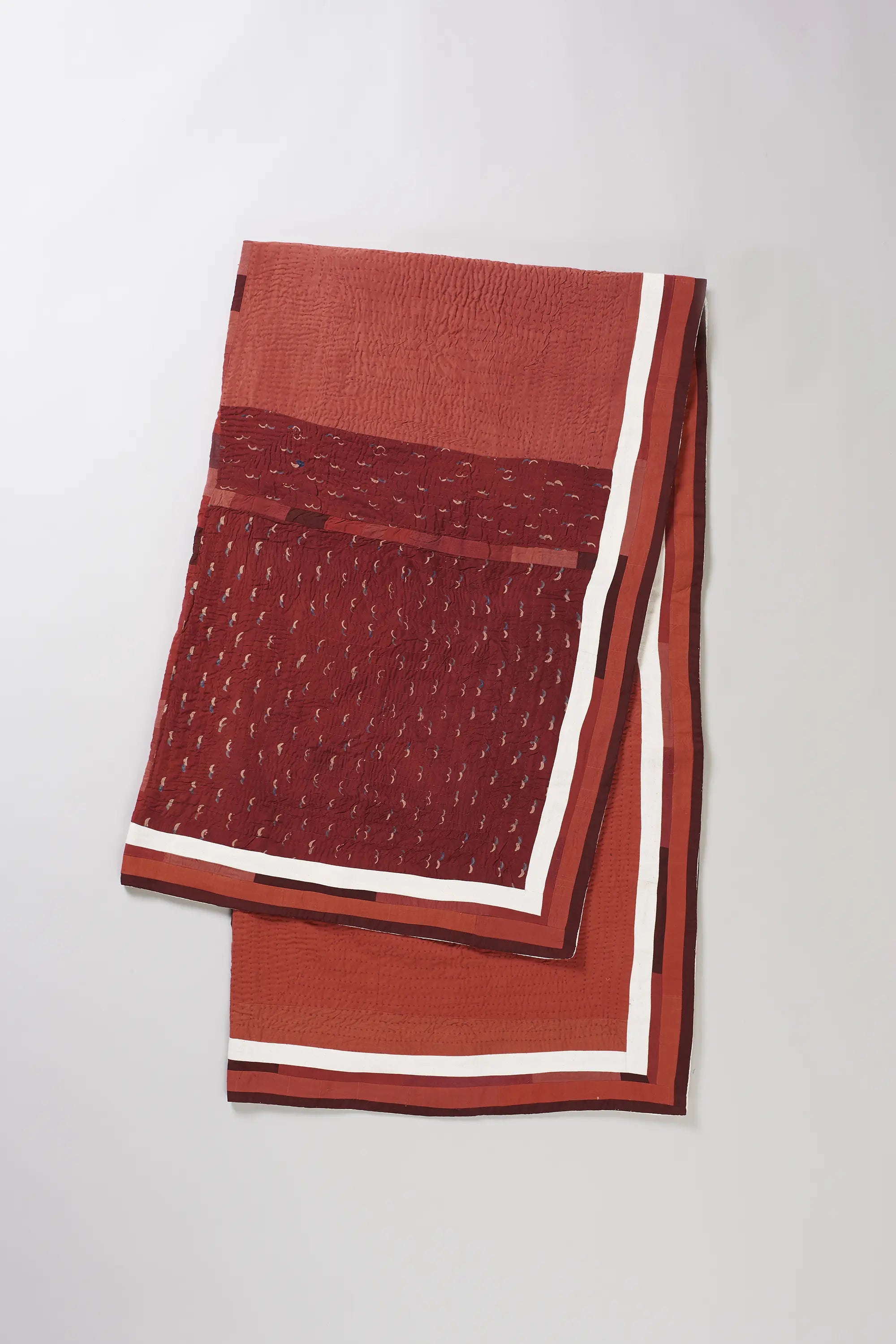Folded red quilt on light grey background