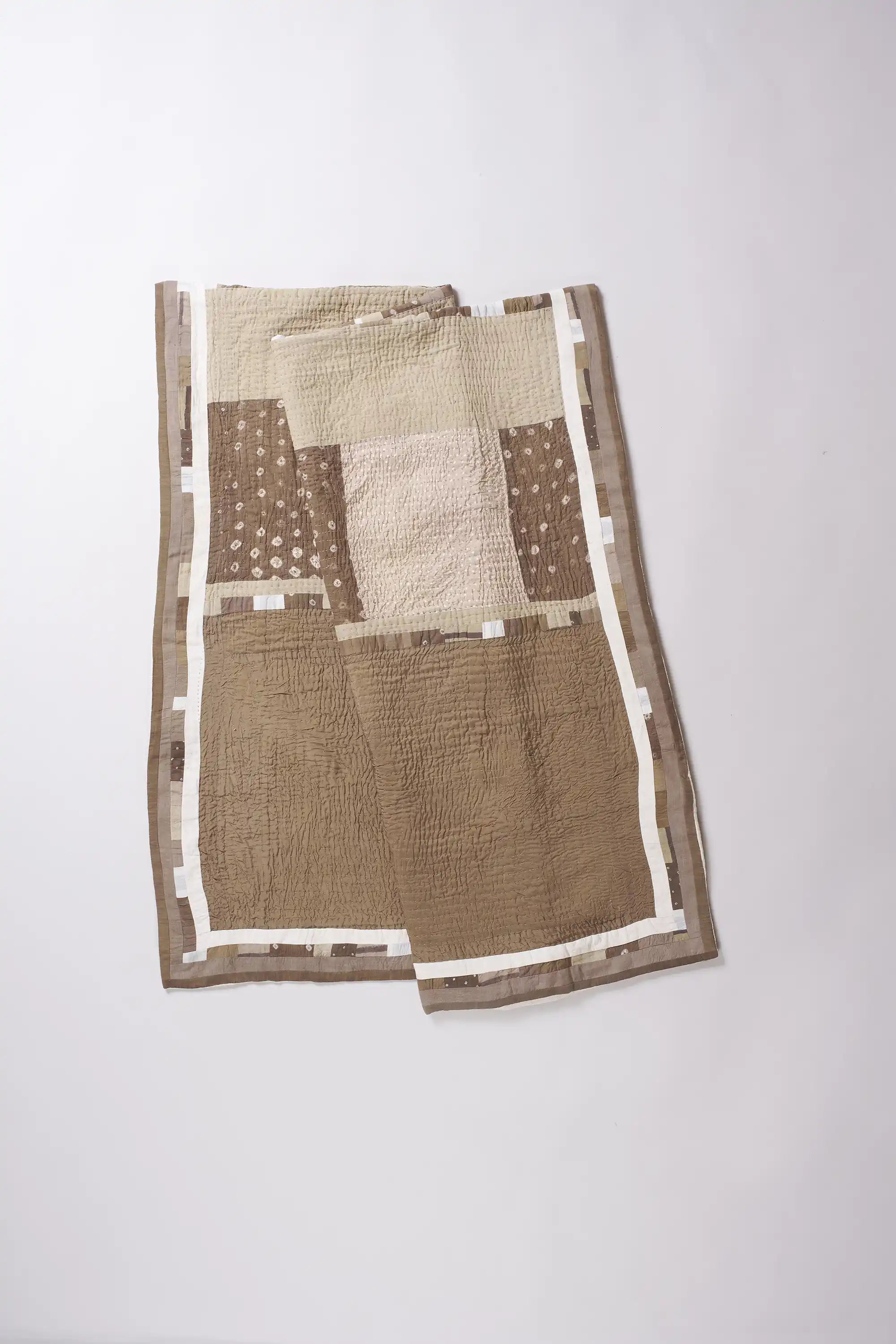 Patchwork quilt with brown and beige patterns on a white background