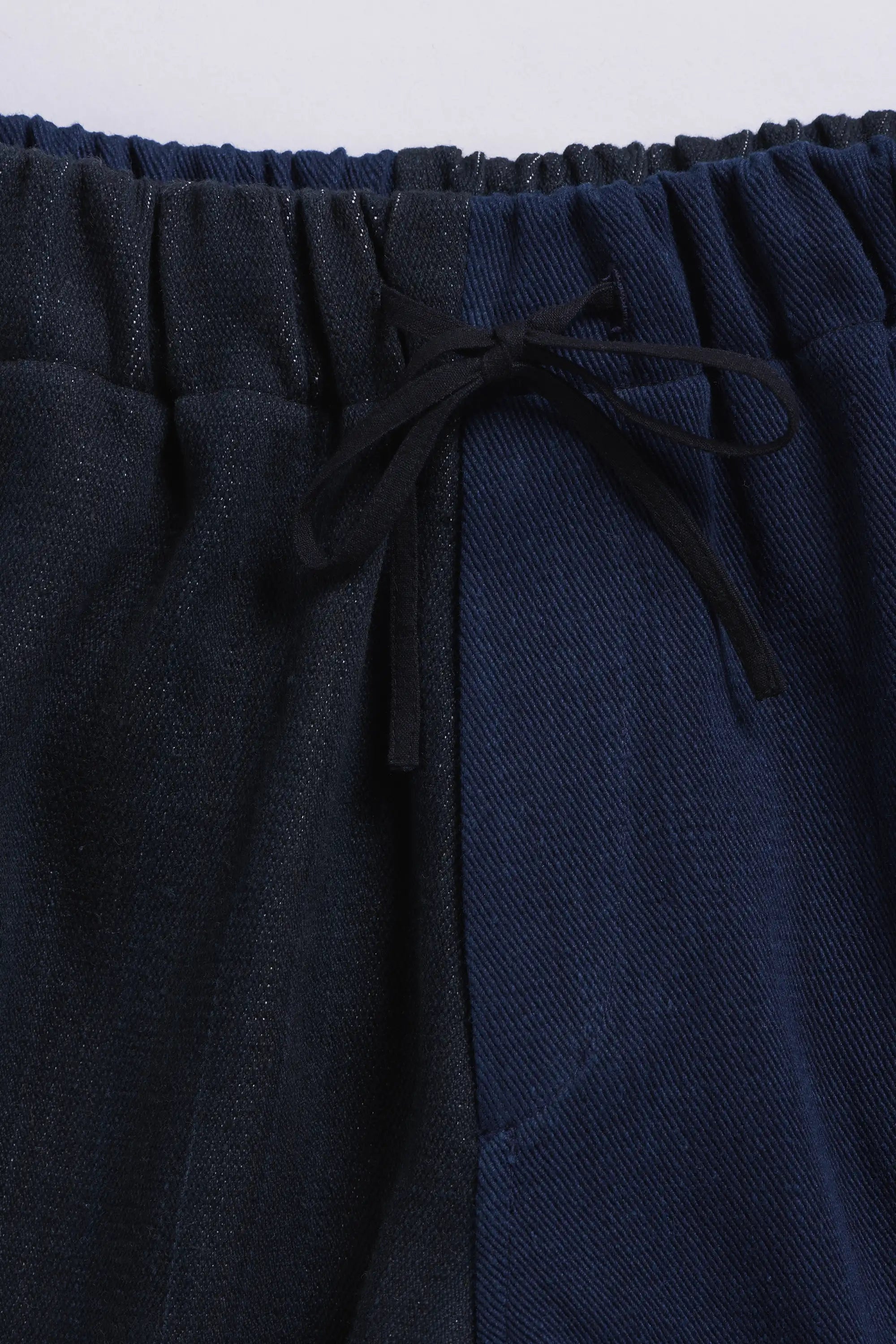 Navy blue pants with a drawstring waist on a light grey background