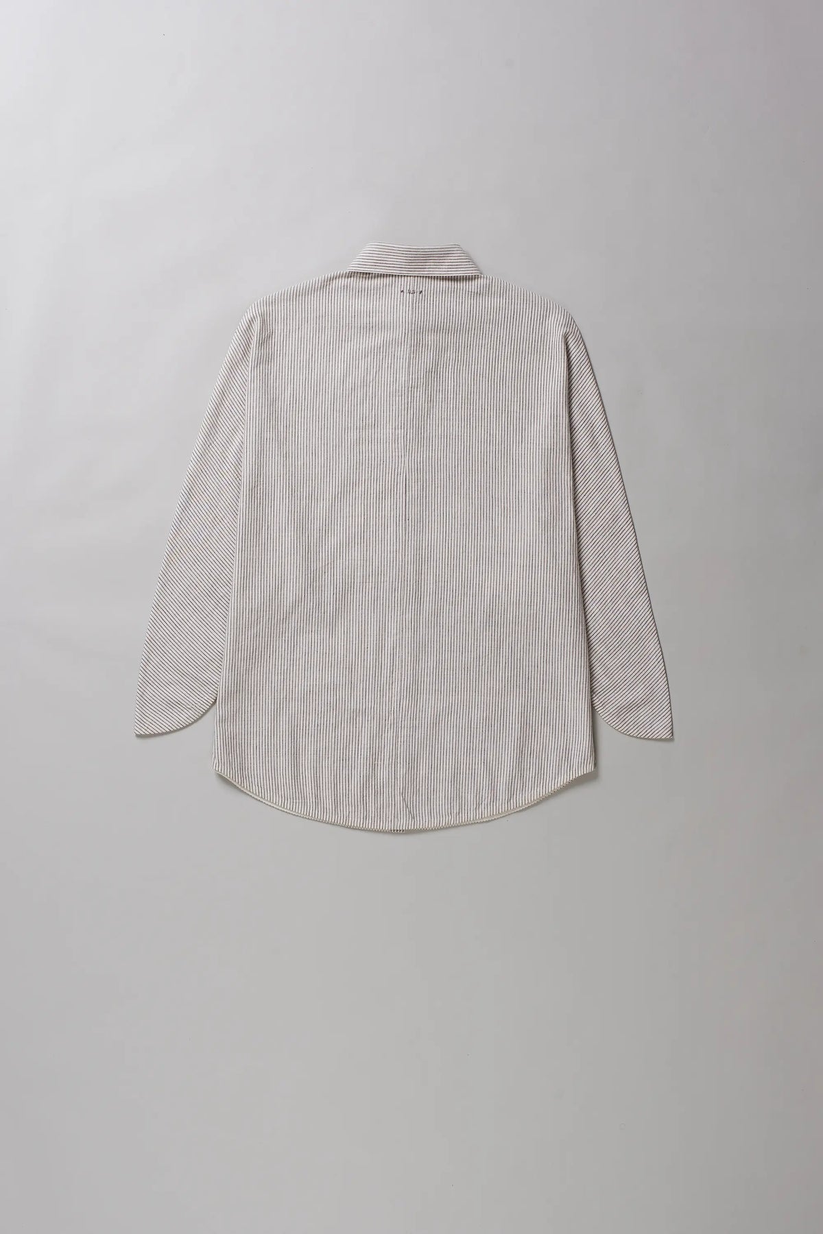 A light beige, long-sleeve shirt shown from the back, laid flat against a neutral light grey background.