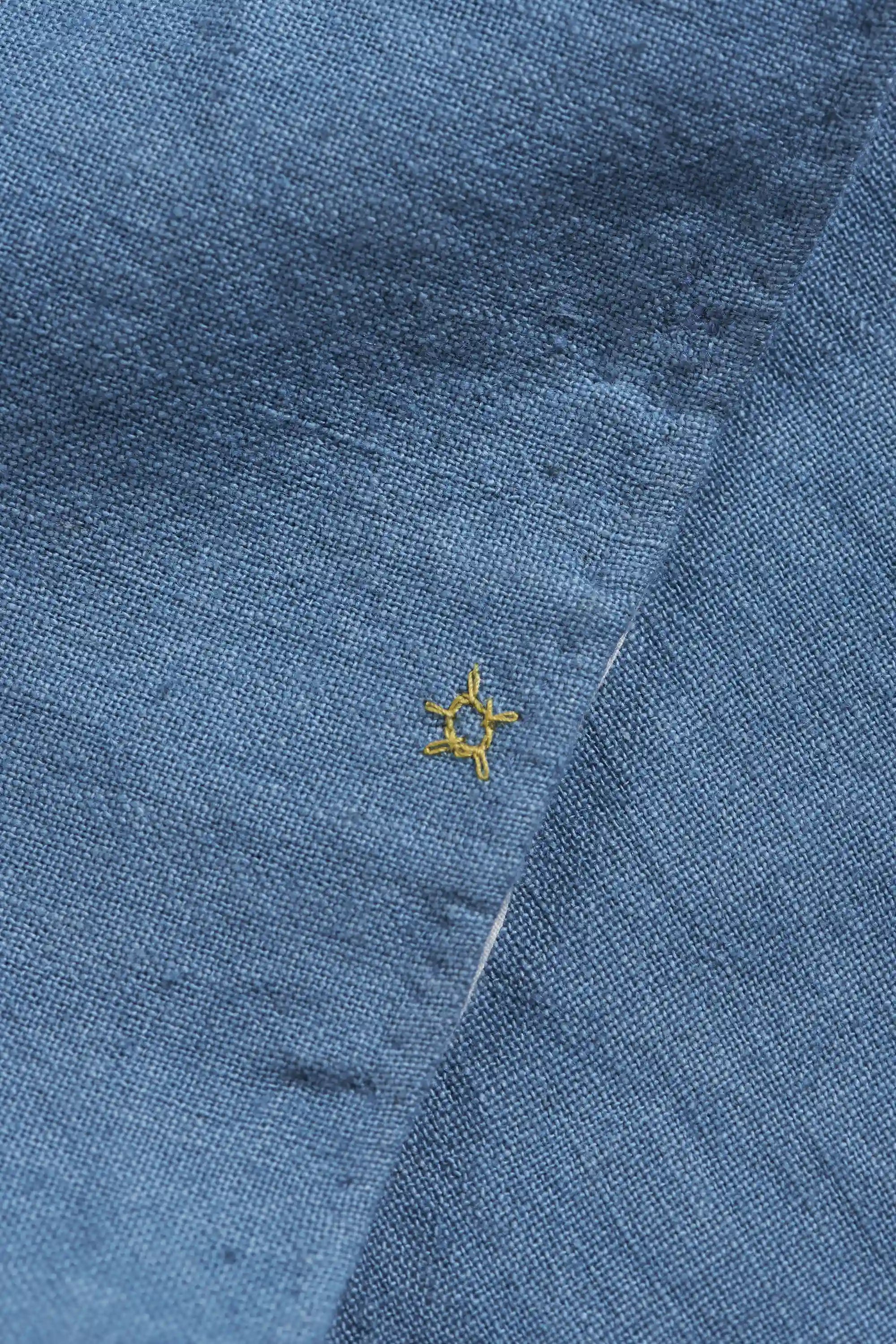 Close-up of a blue fabric with a yellow pehchan star on a shirt
