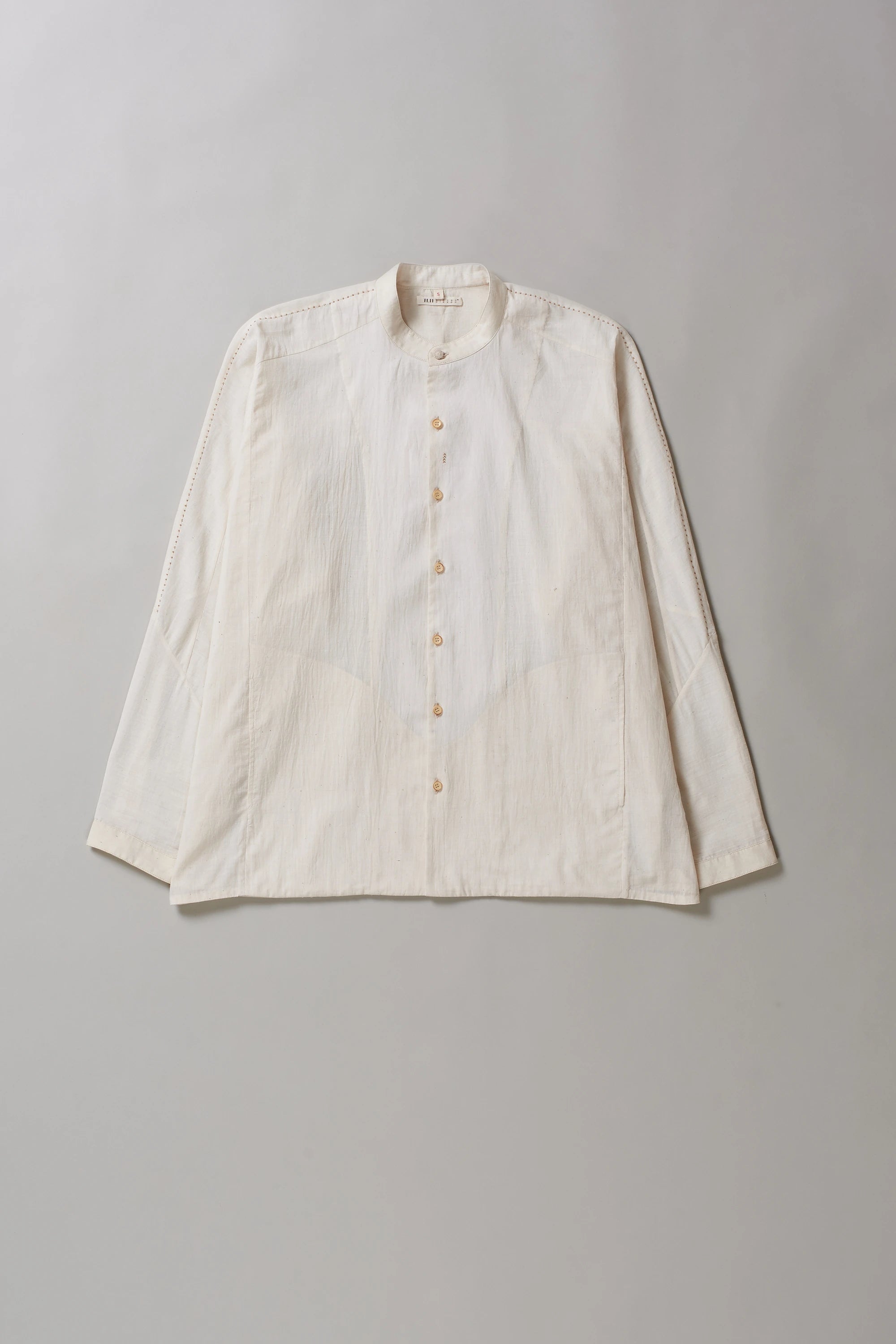 Front image of ecru cotton shirt with hand detailing on a grey background