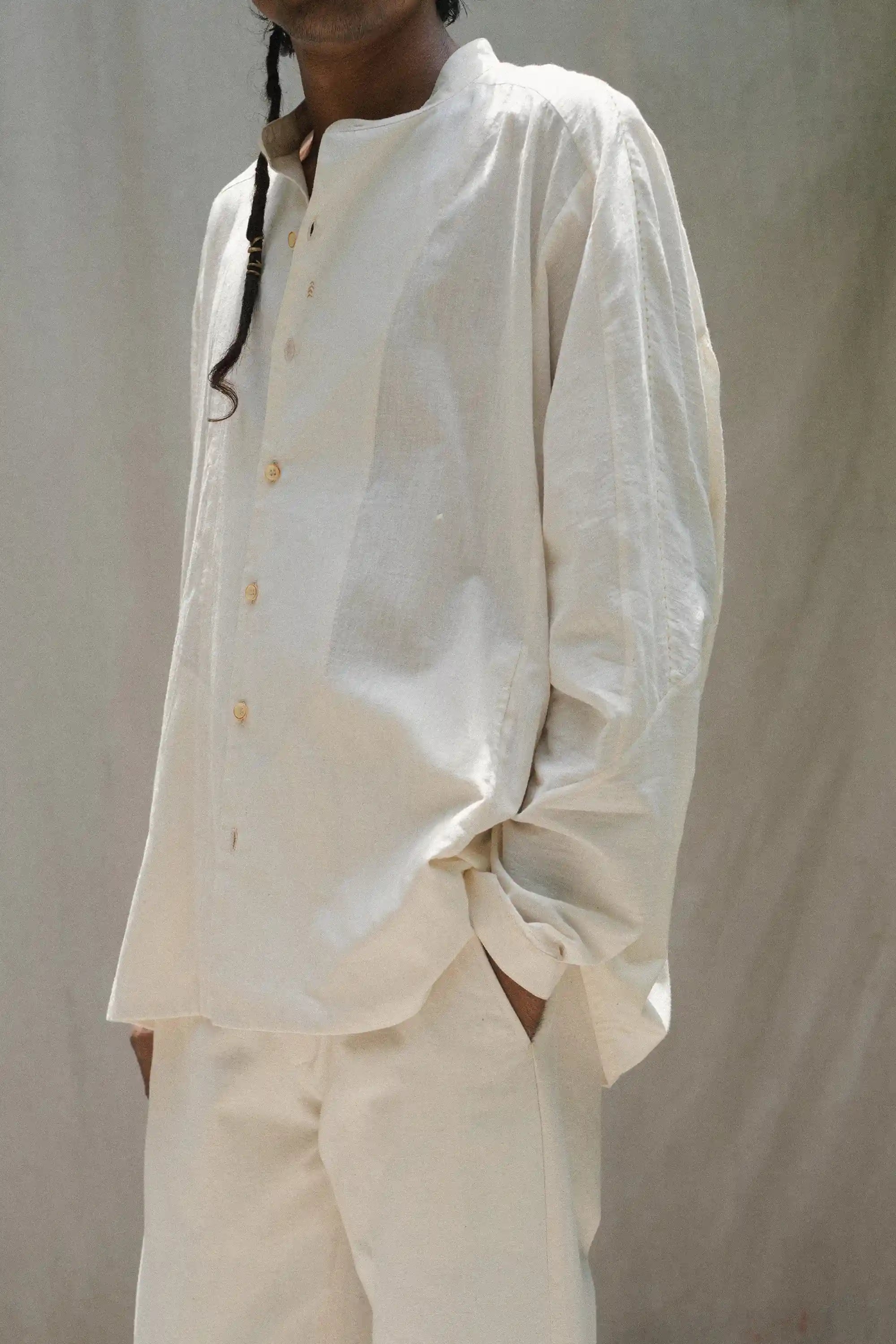 Person wearing a ecru outfit against a plain background