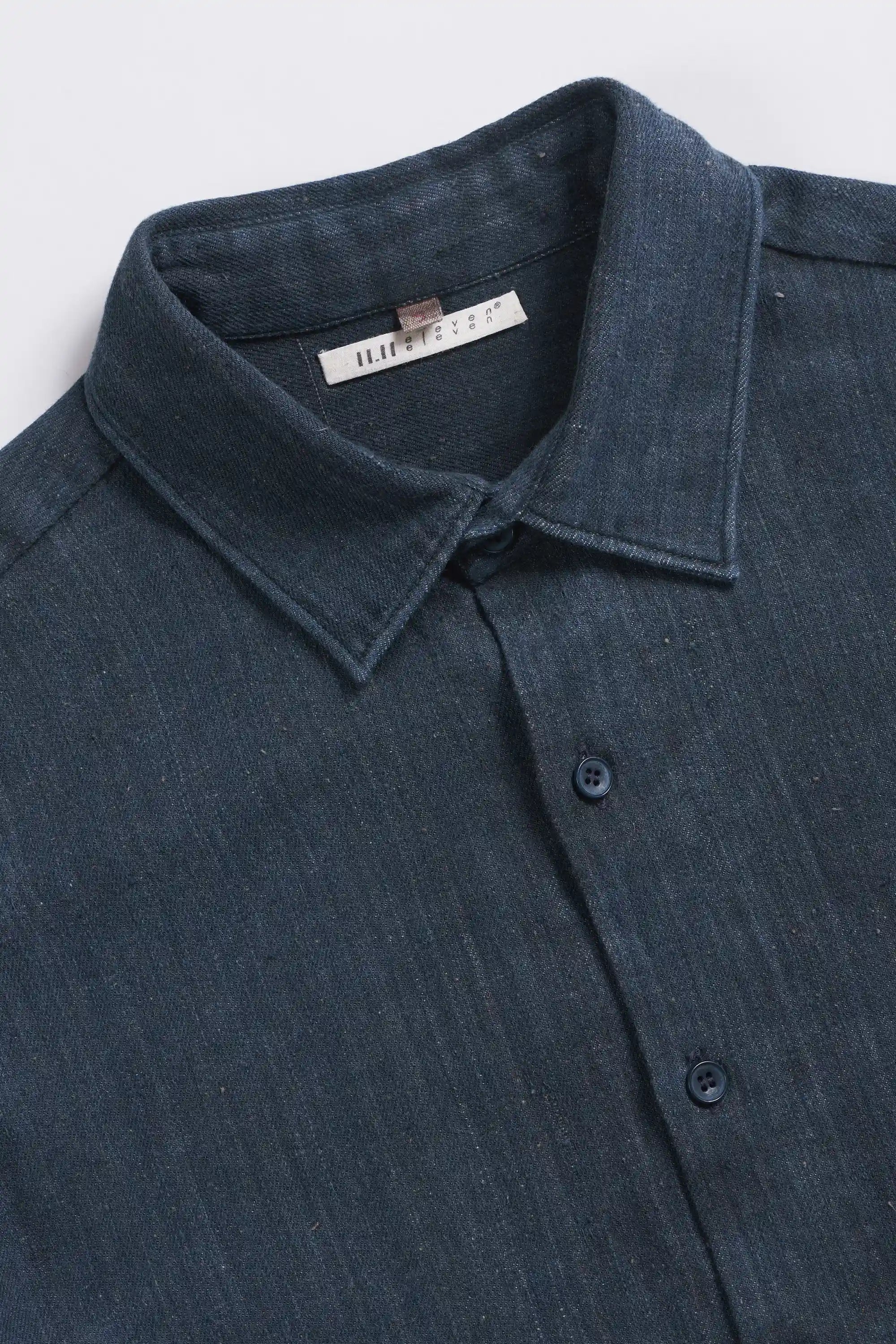 Close-up of a blue shirt with collar and buttons on a light grey background