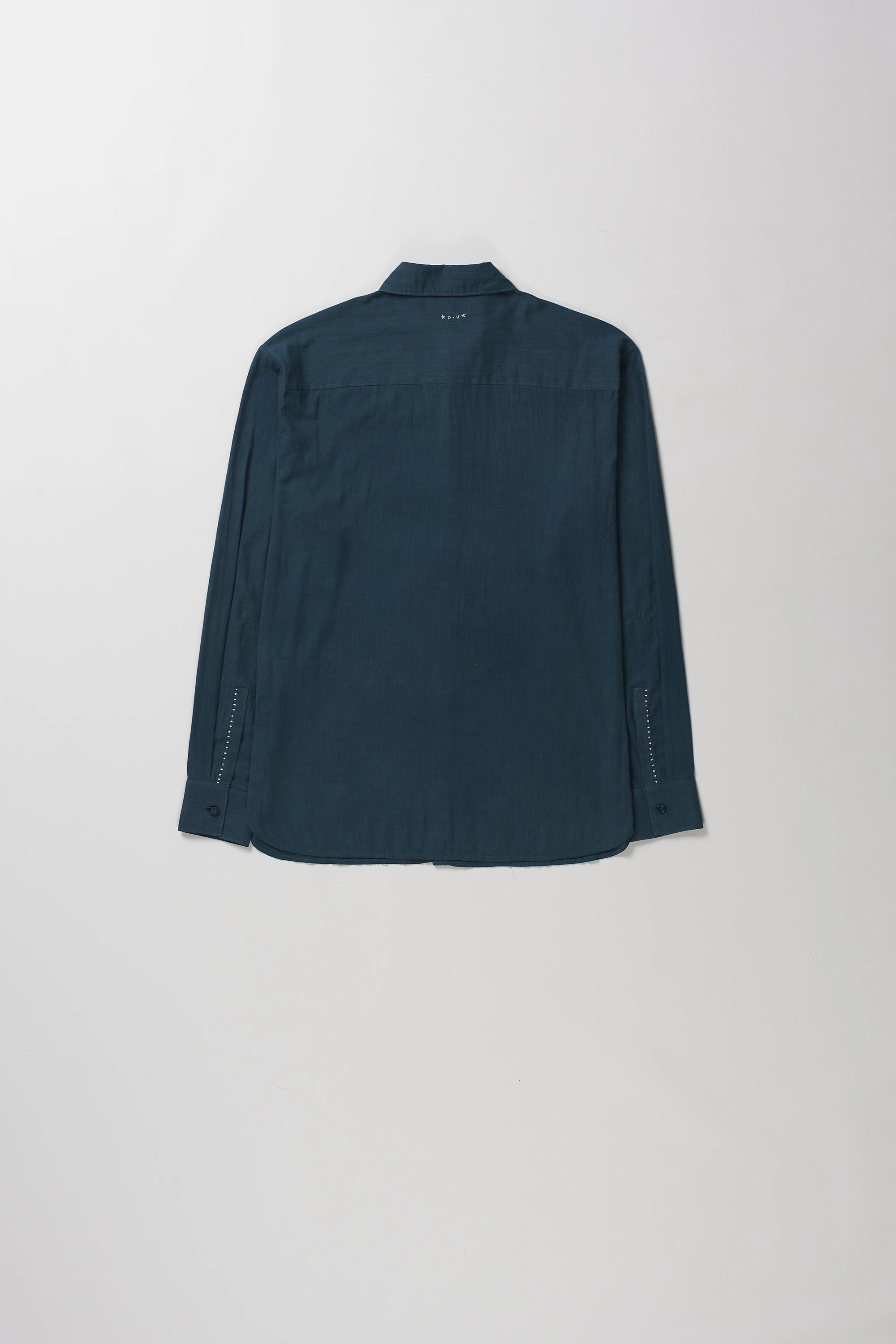 Back shot of long-sleeve button-up shirt with a pointed collar, laid flat against a light gray background.