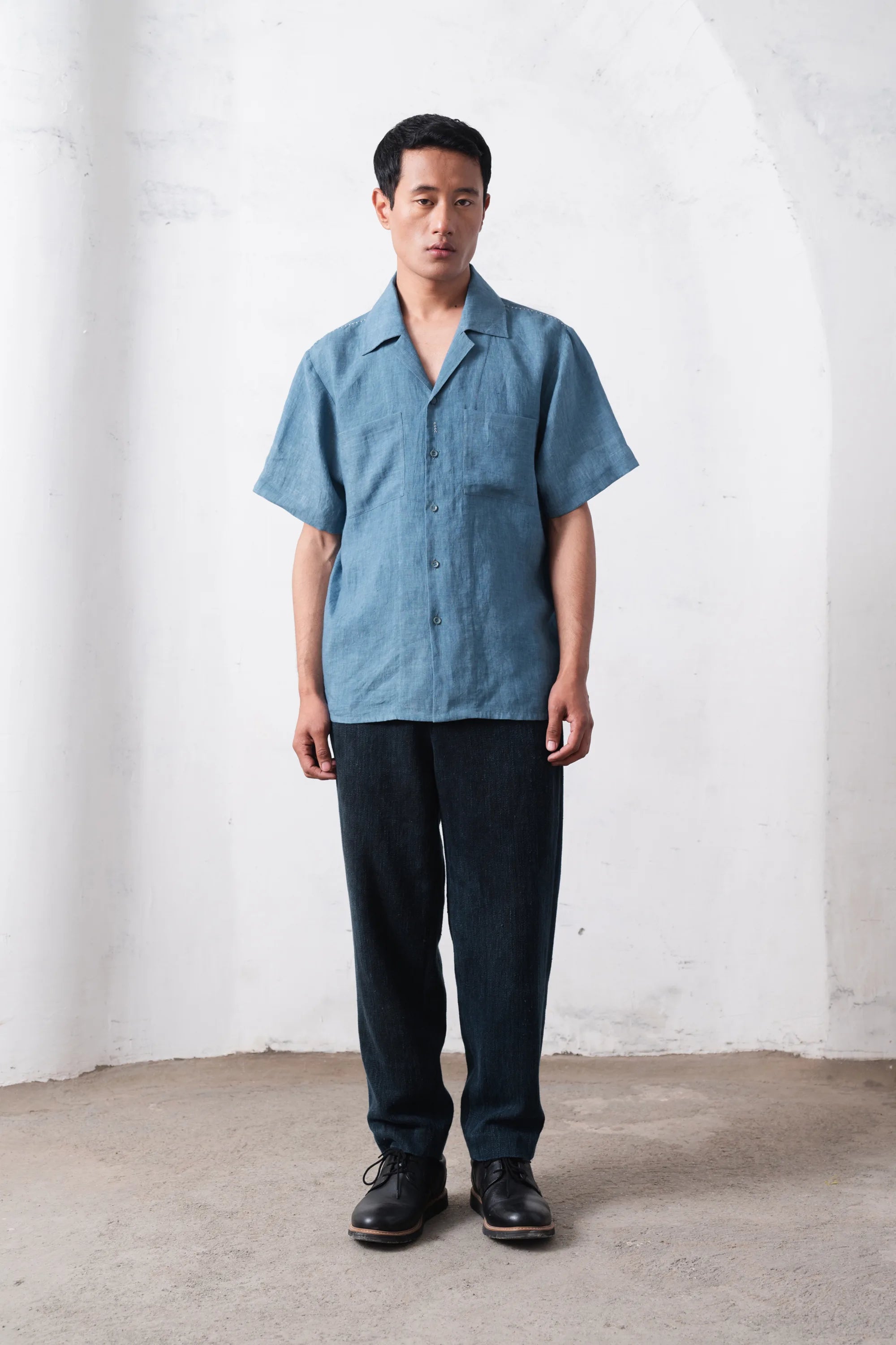 Man wearing a light blue shirt and dark pants 