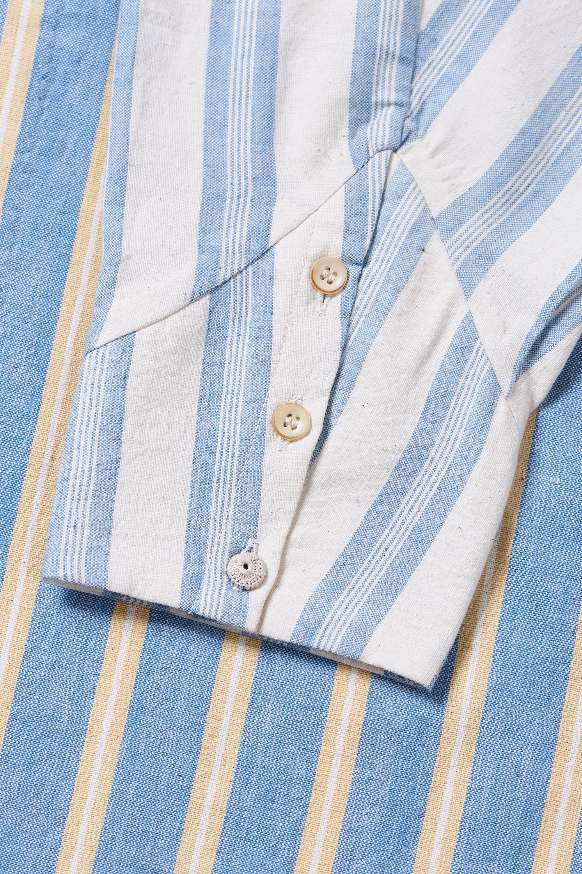 Close-up of a blue and white striped shirt with buttons and sleeve