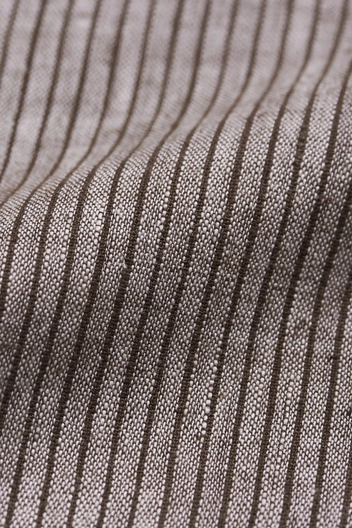 Close-up of a woven fabric with a fine vertical stripe pattern in dark brown on a light beige background.