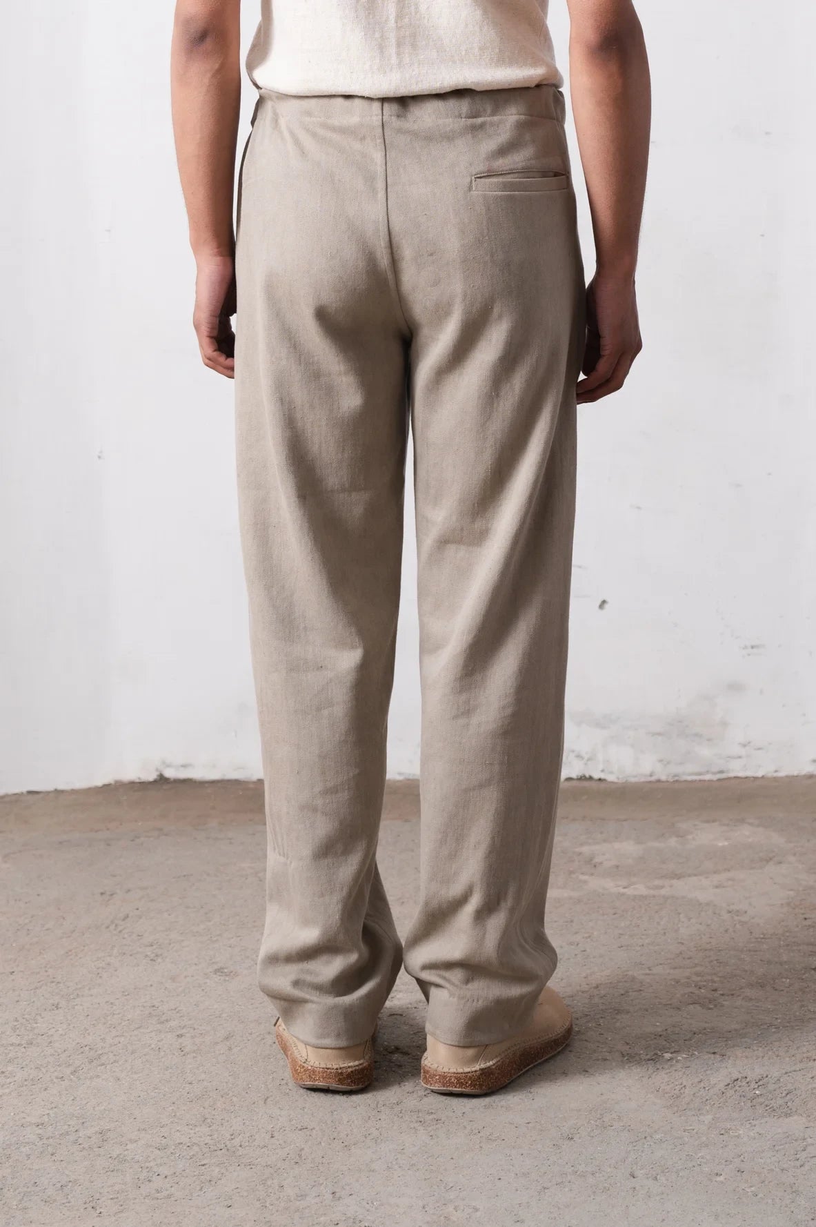 Person wearing pants standing against a light grey wall