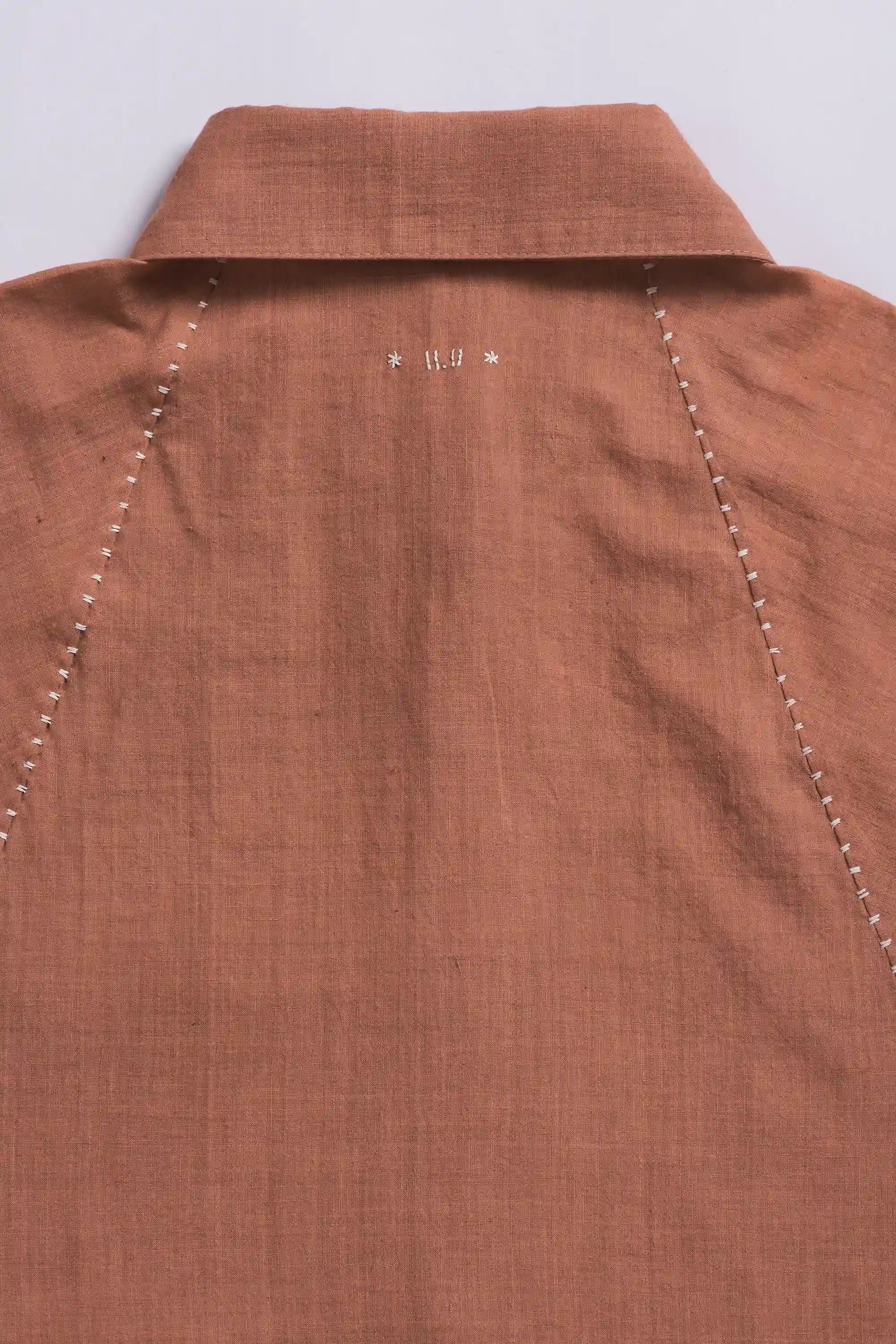 Orange rust shirt with a collar and hand detailing on a light grey background