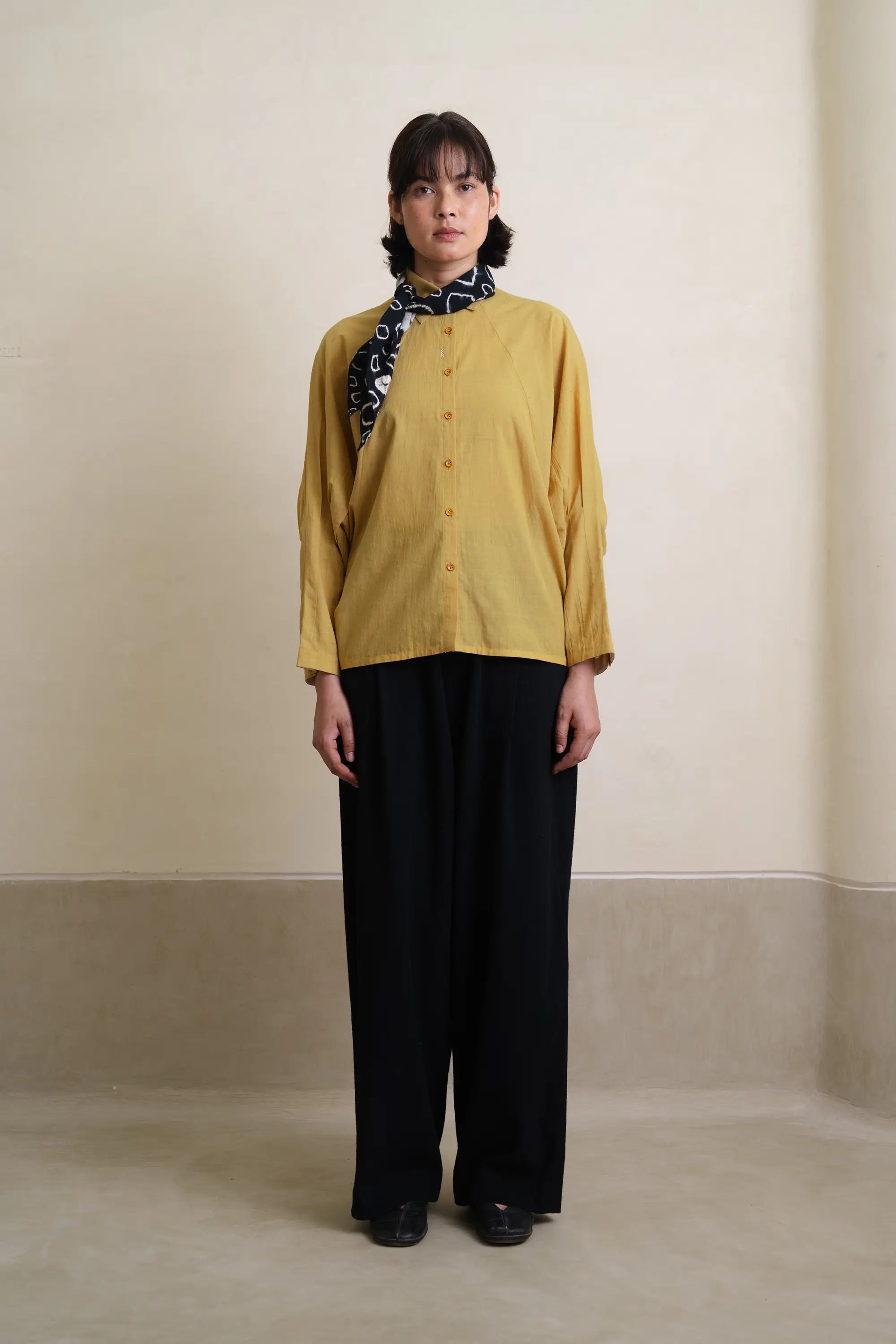 A woman wearing ochre yellow shirt with black bandana