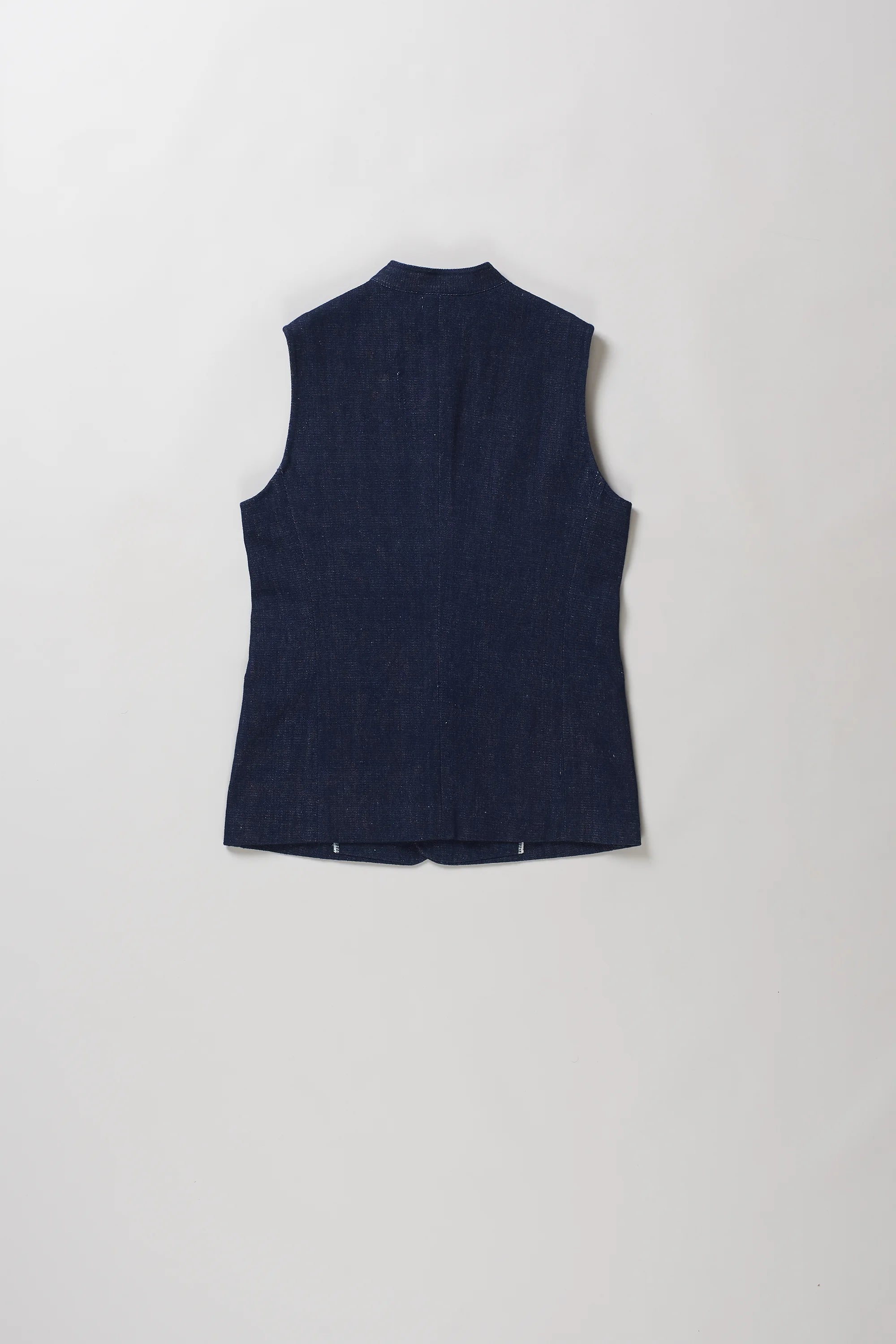 Back shot of sleeveless black indigo vest with a mandarin collar and front button closure, laid flat against a light gray background.