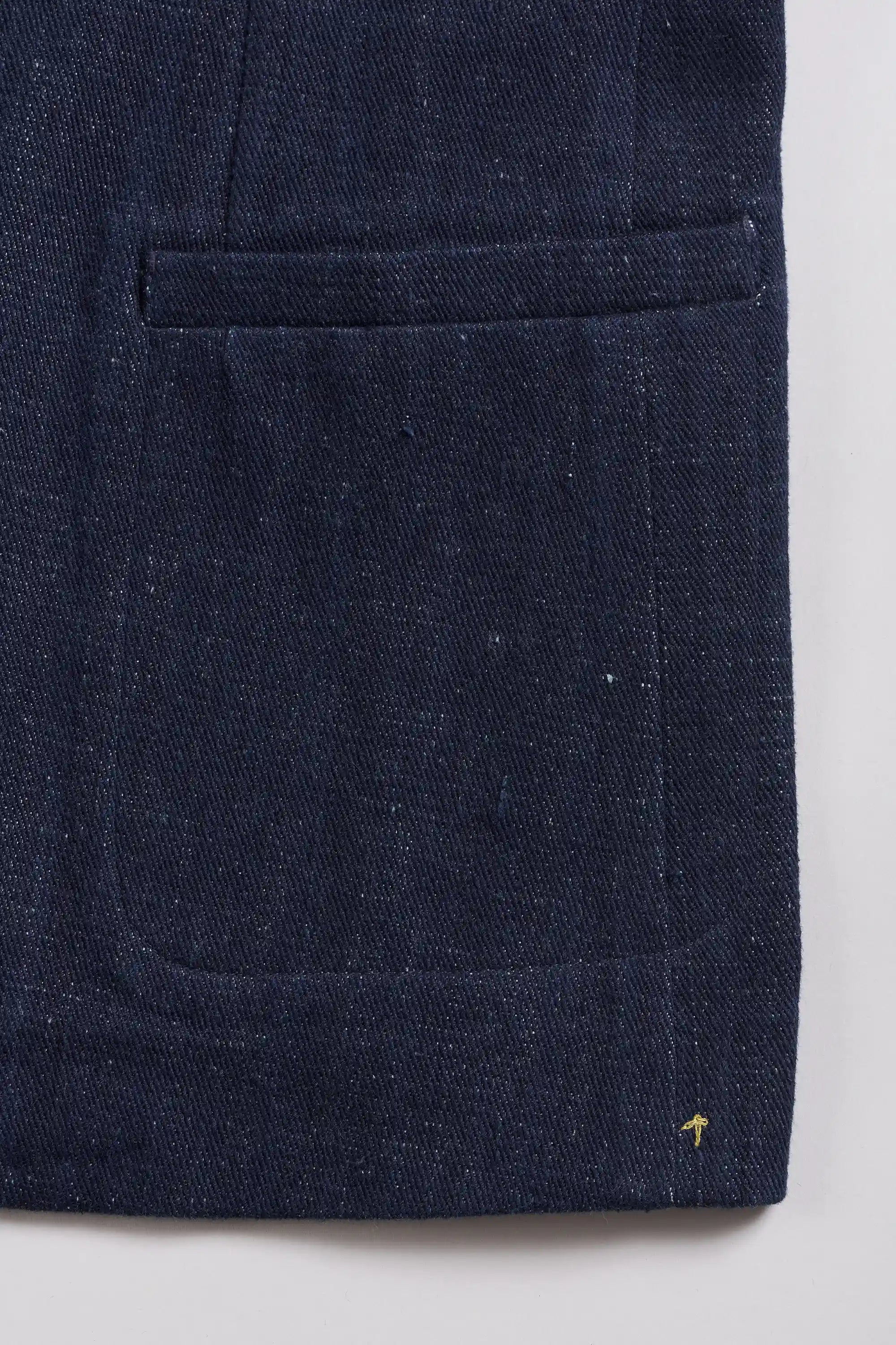 Close-up of jacket, showing a pocket and a small yellow embroidered logo near the bottom right.