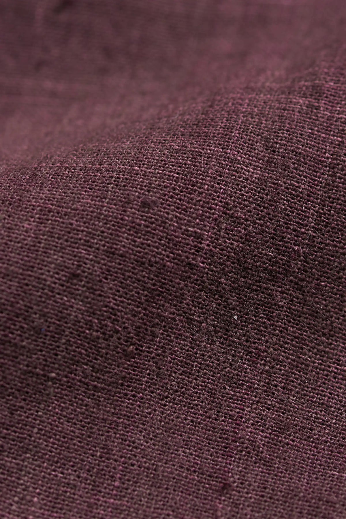 A close-up of textured fabric in a purple color, showing the weave and fine fibers.