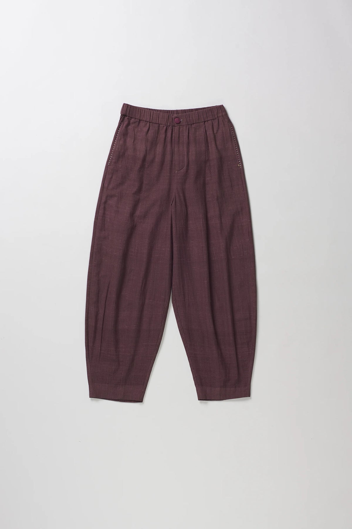 A pair of loose-fitting, dark plum-colored cropped pants with a subtle grid pattern, laid flat against a light grey background.