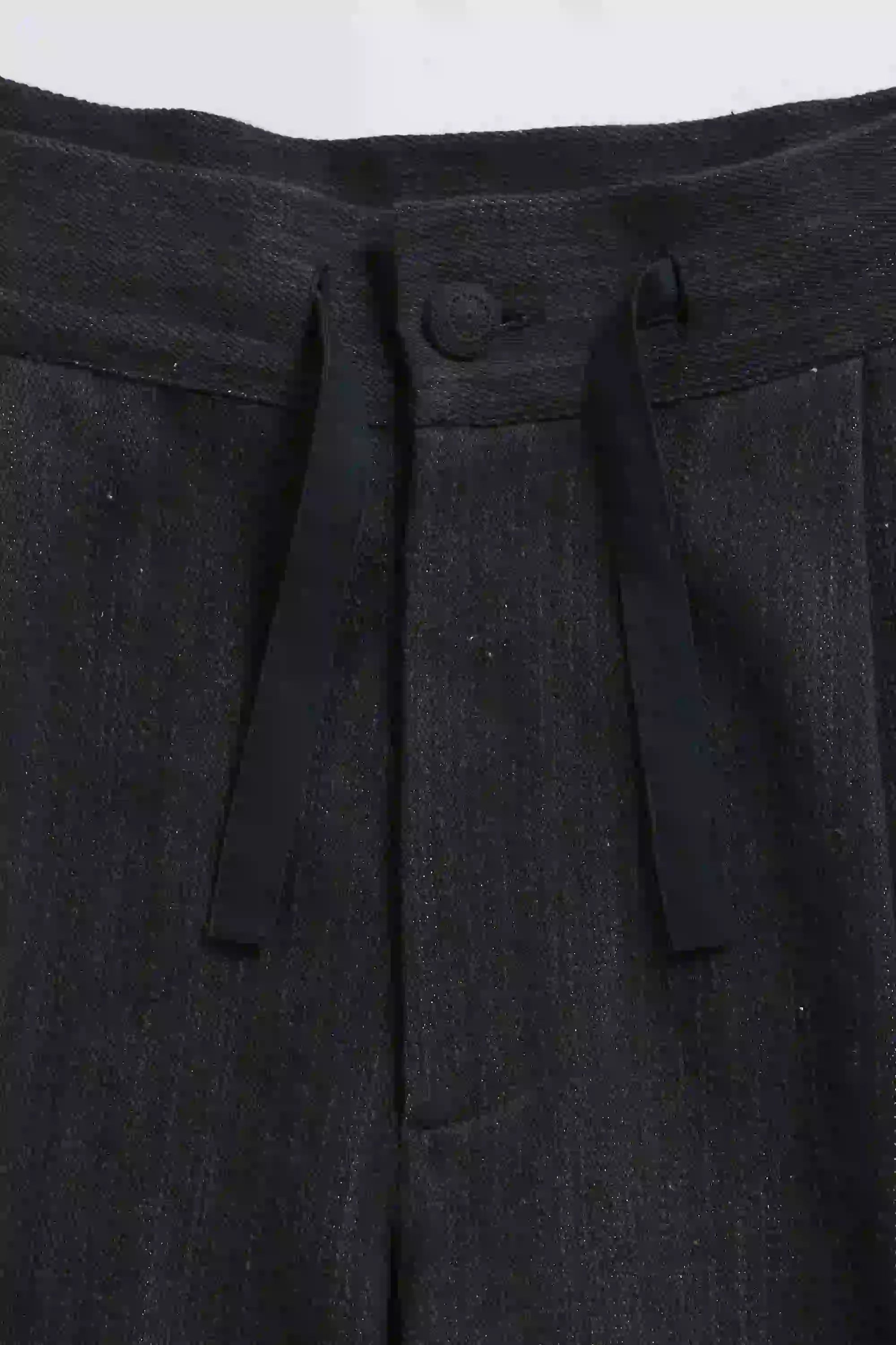 Close-up of dark gray pants with a focus on the waistband and pleats.