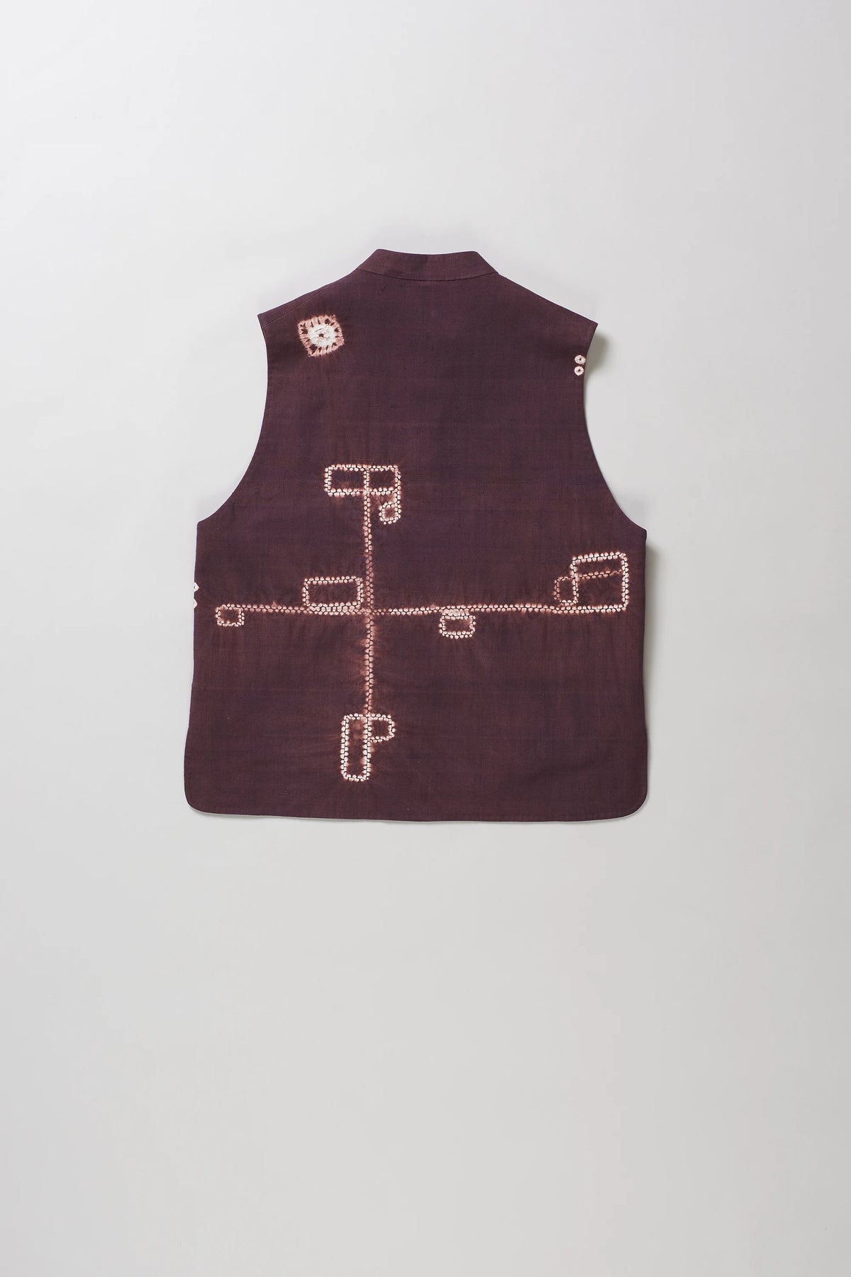 A sleeveless vest with shibori patterns in light colour and white on the back, displayed flat against a light grey background.