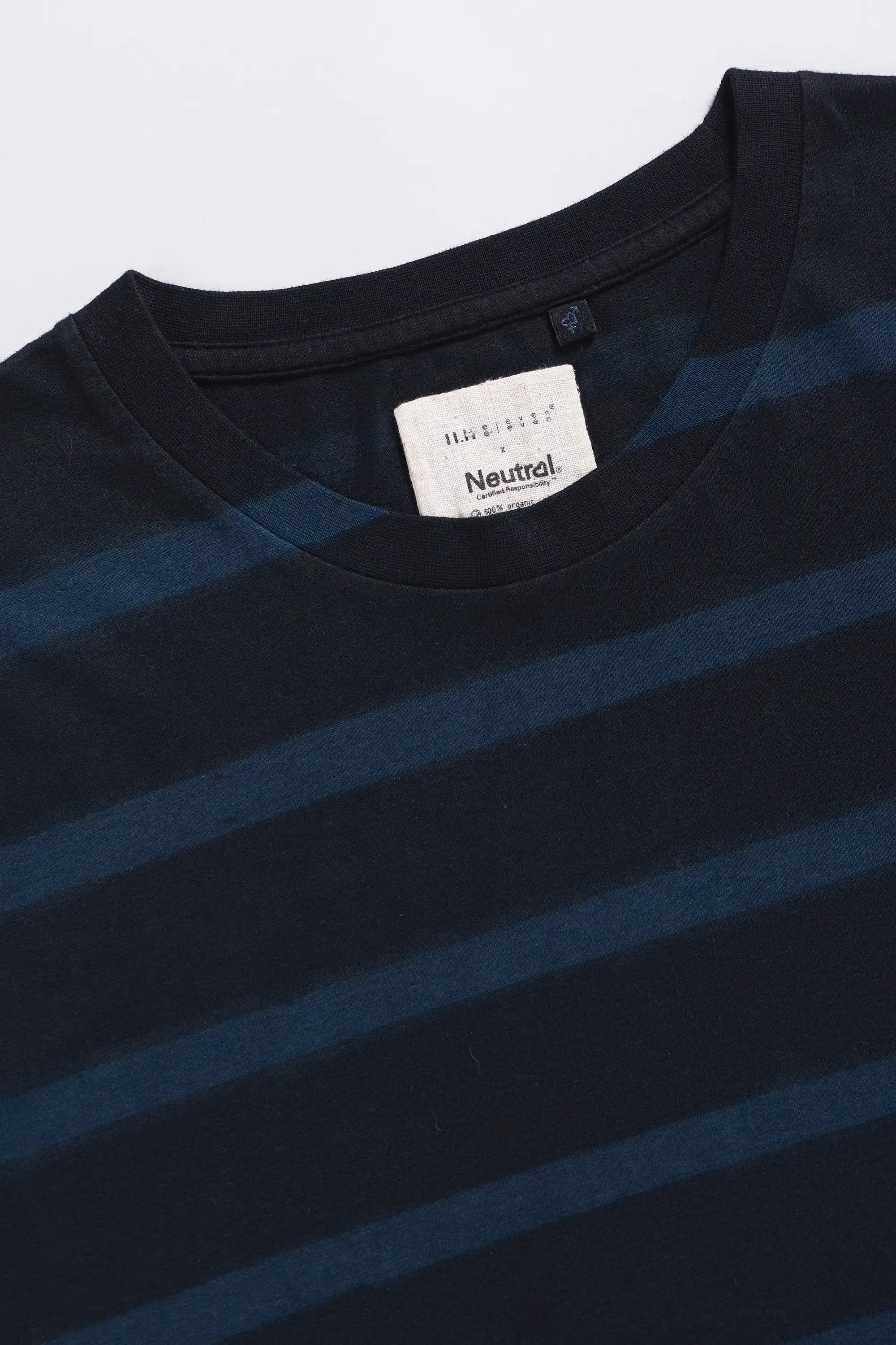 Close-up of a black and blue striped t-shirt with a brand label on a light grey background