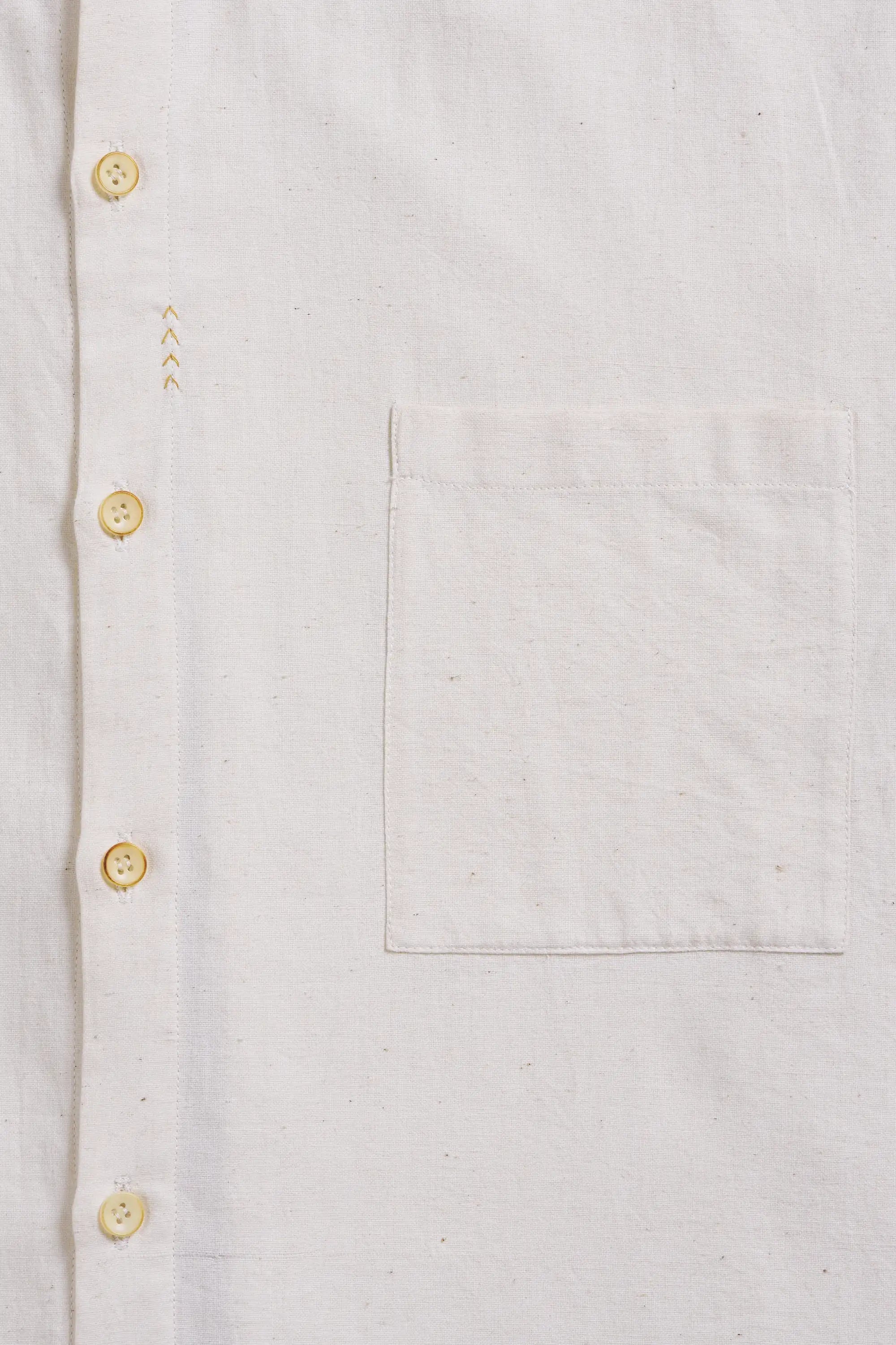Close-up of a light-colored shirt with buttons details and a pocket
