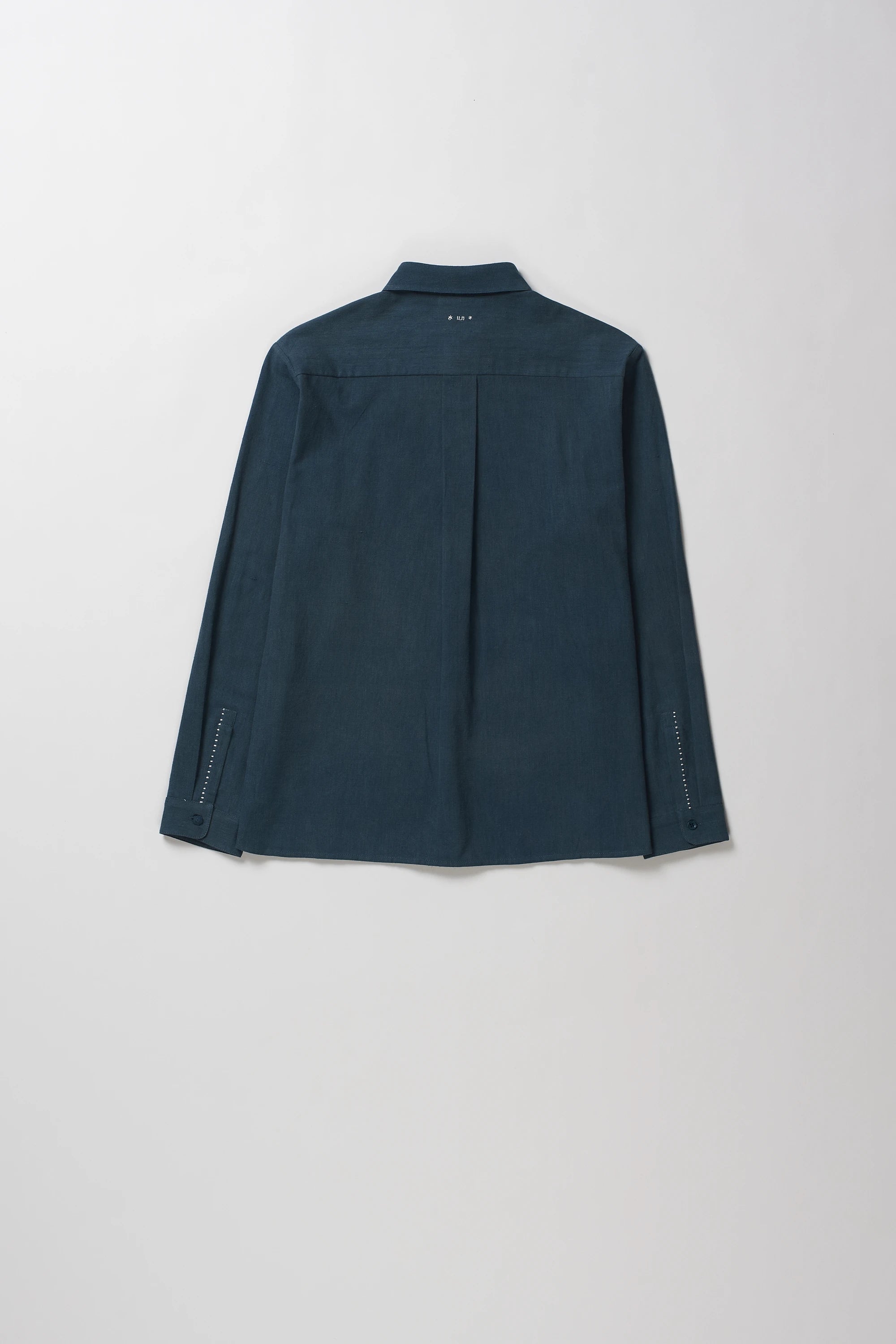 Back shot of long-sleeve button-up shirt with a pointed collar, laid flat against a light gray background.