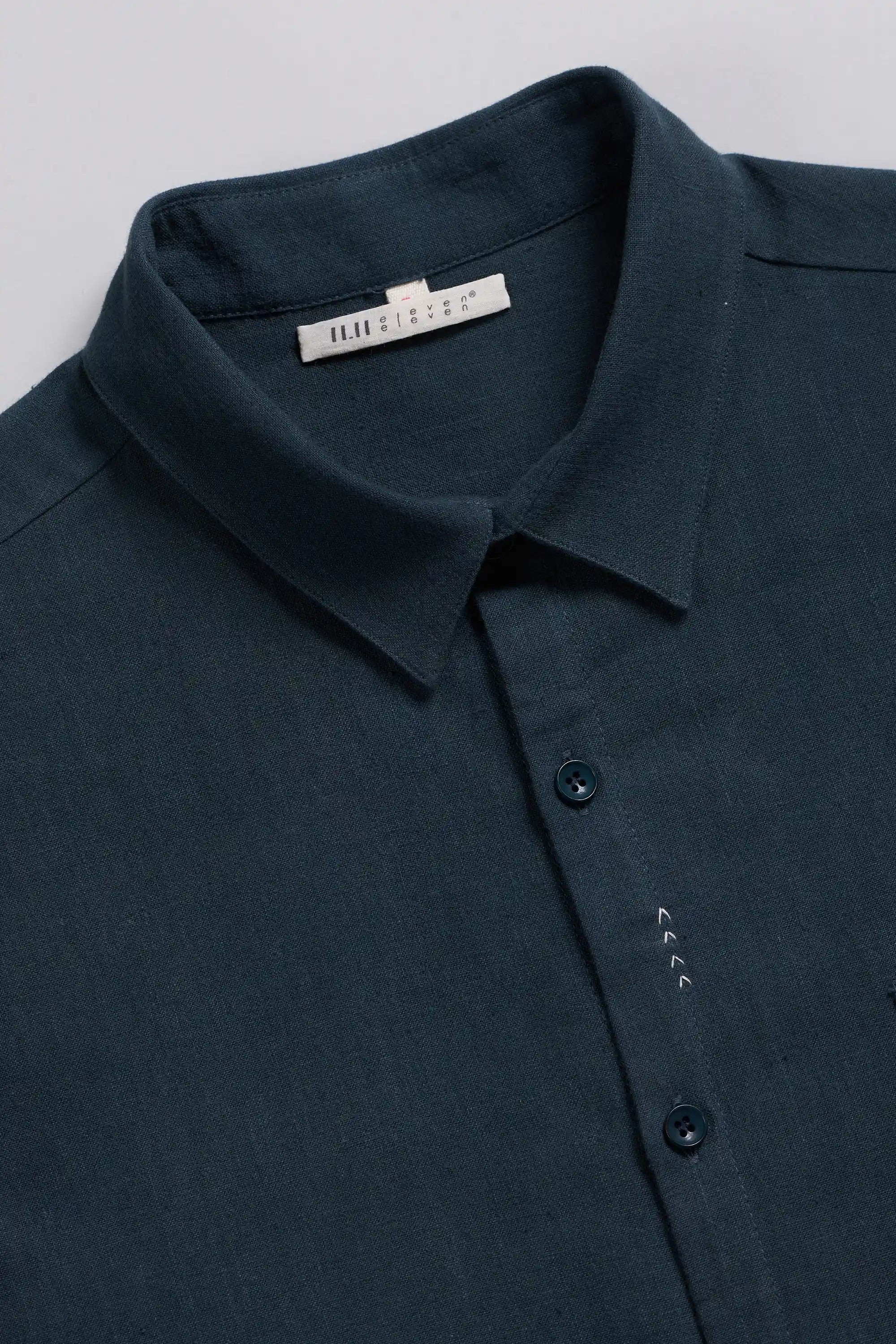 A close-up of a black indigo button-down shirt with a pointed collar.