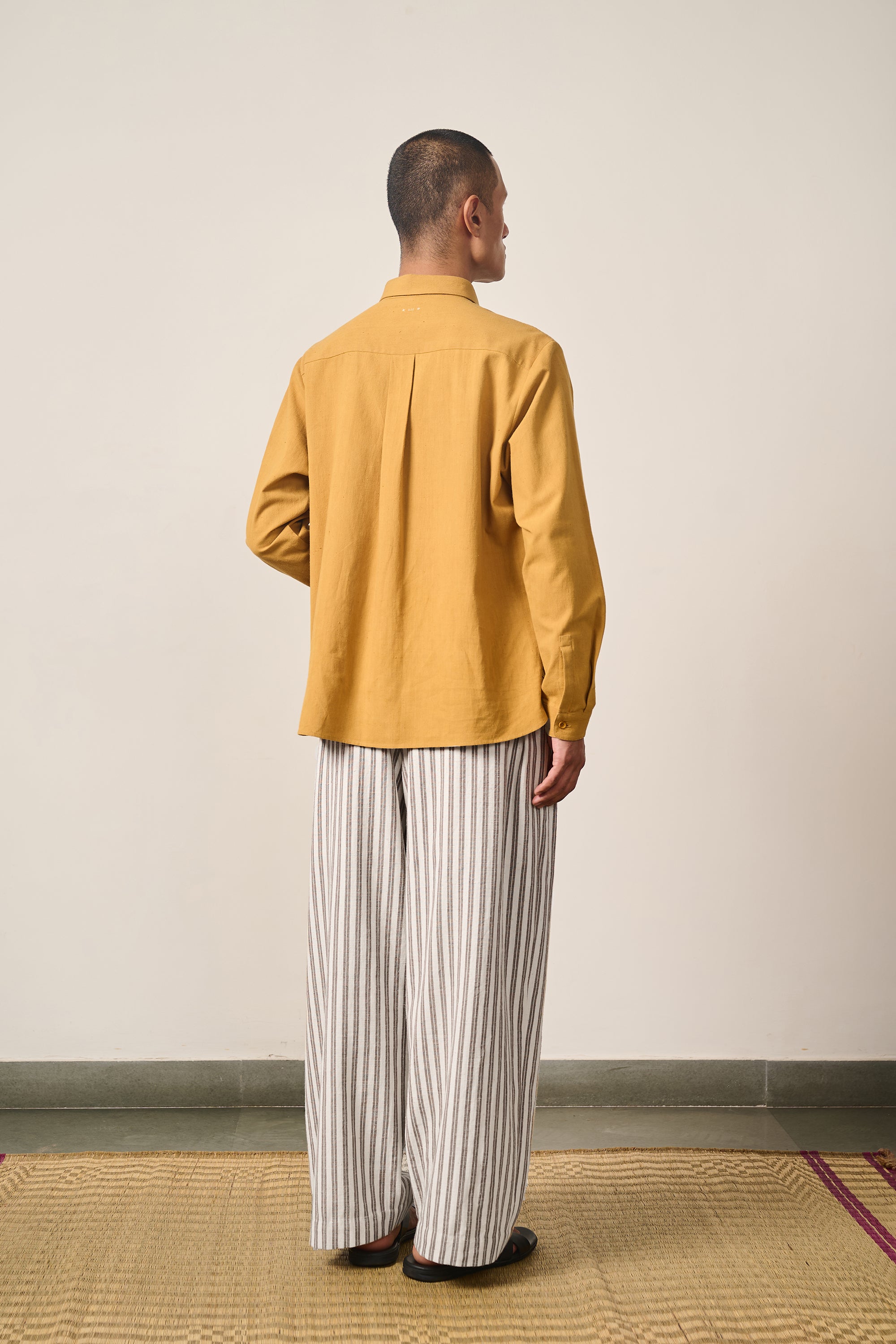 A back shot of a man wearing mustard yellow shirt