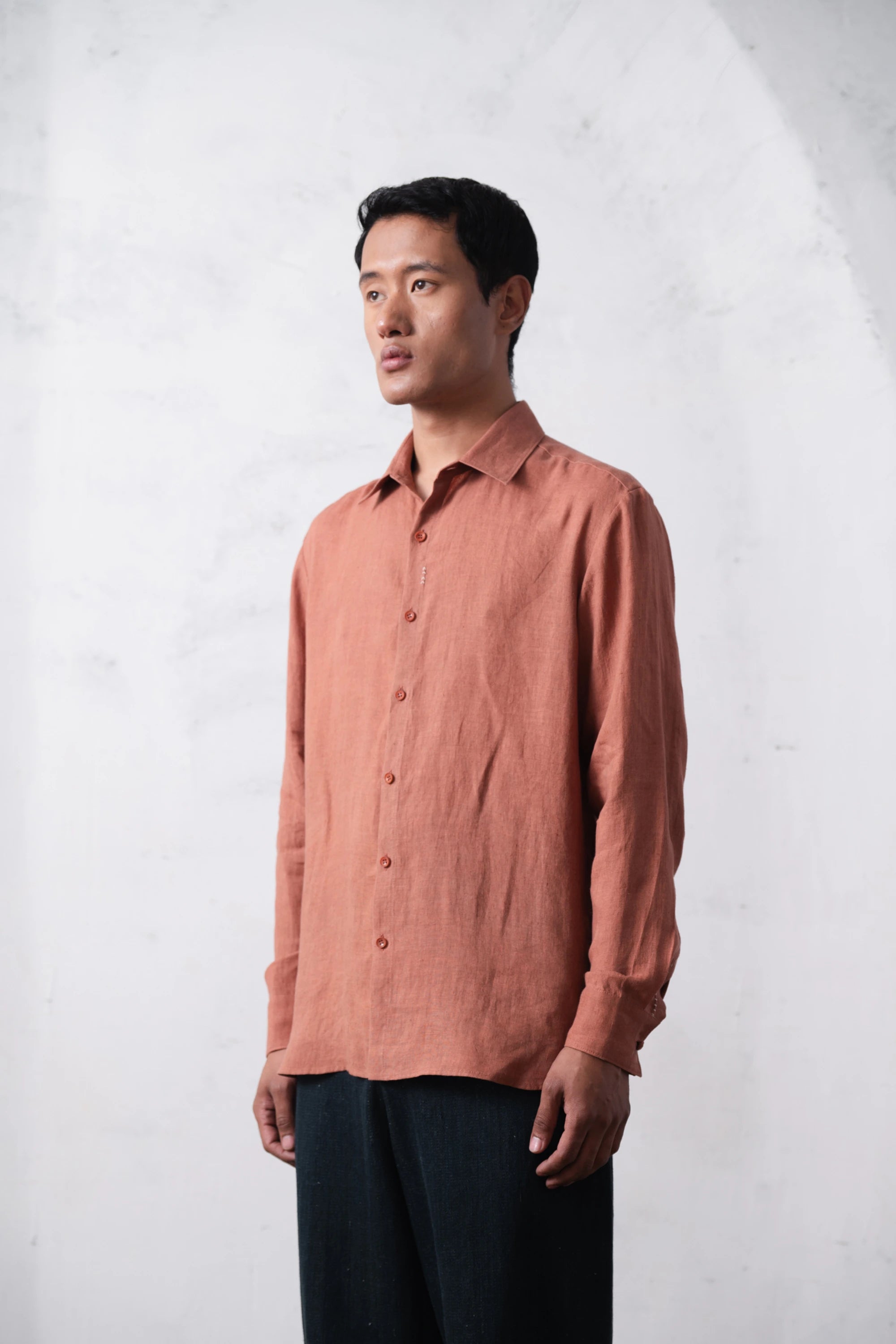 Man wearing a orange rust shirt against a light grey background