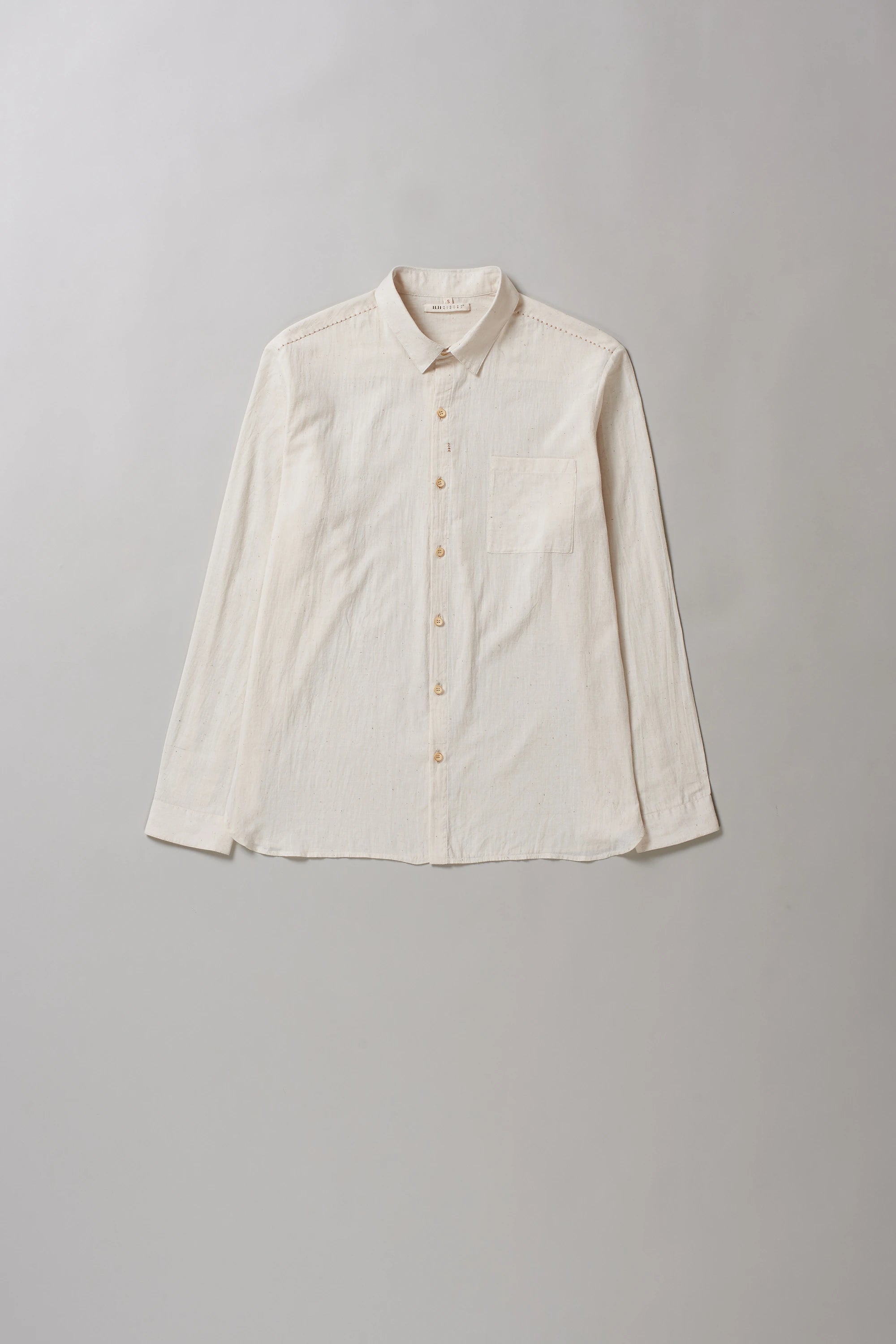 Front image of ecru shirt with hand detailing on a grey background