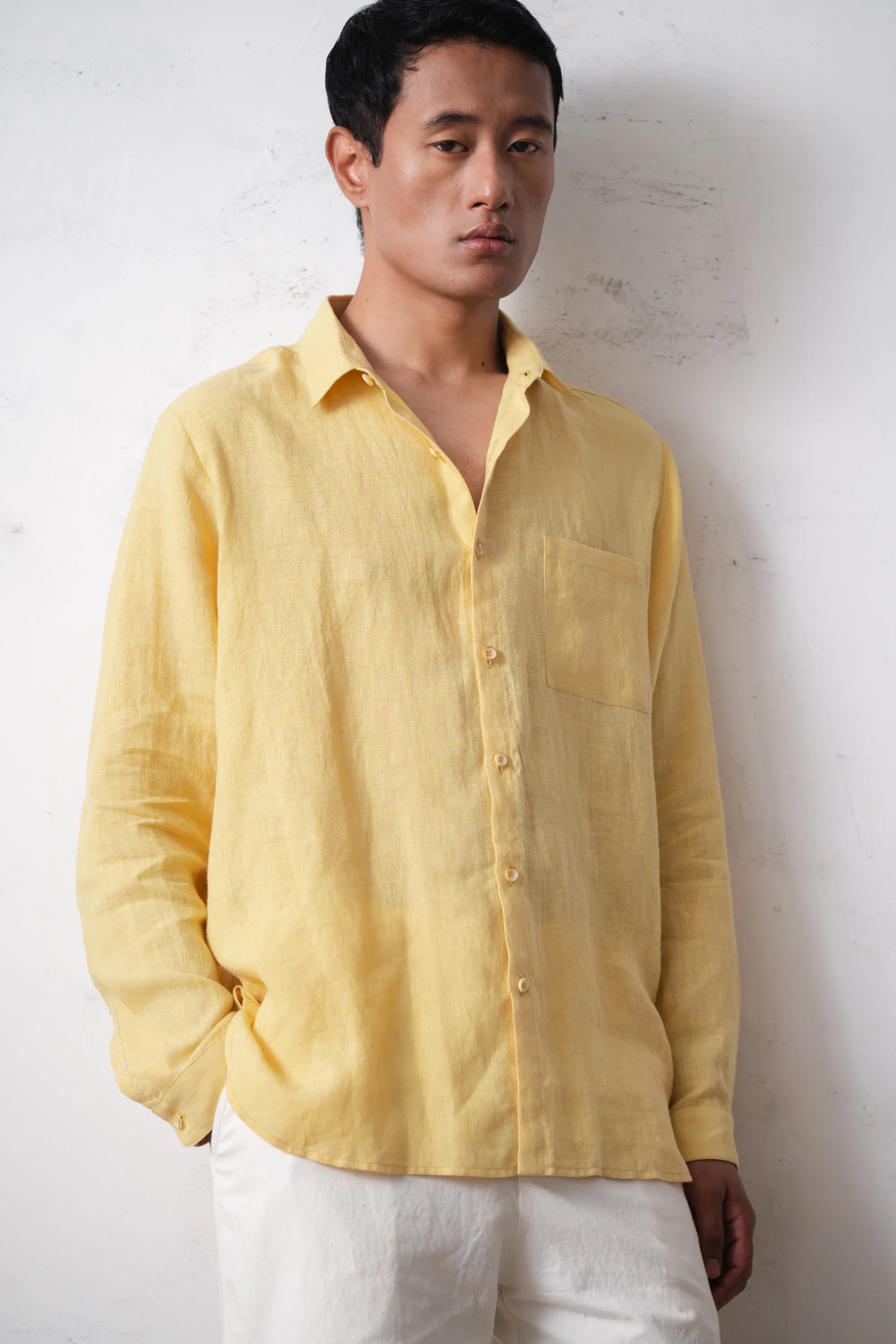Man wearing a light yellow shirt against a light grey background