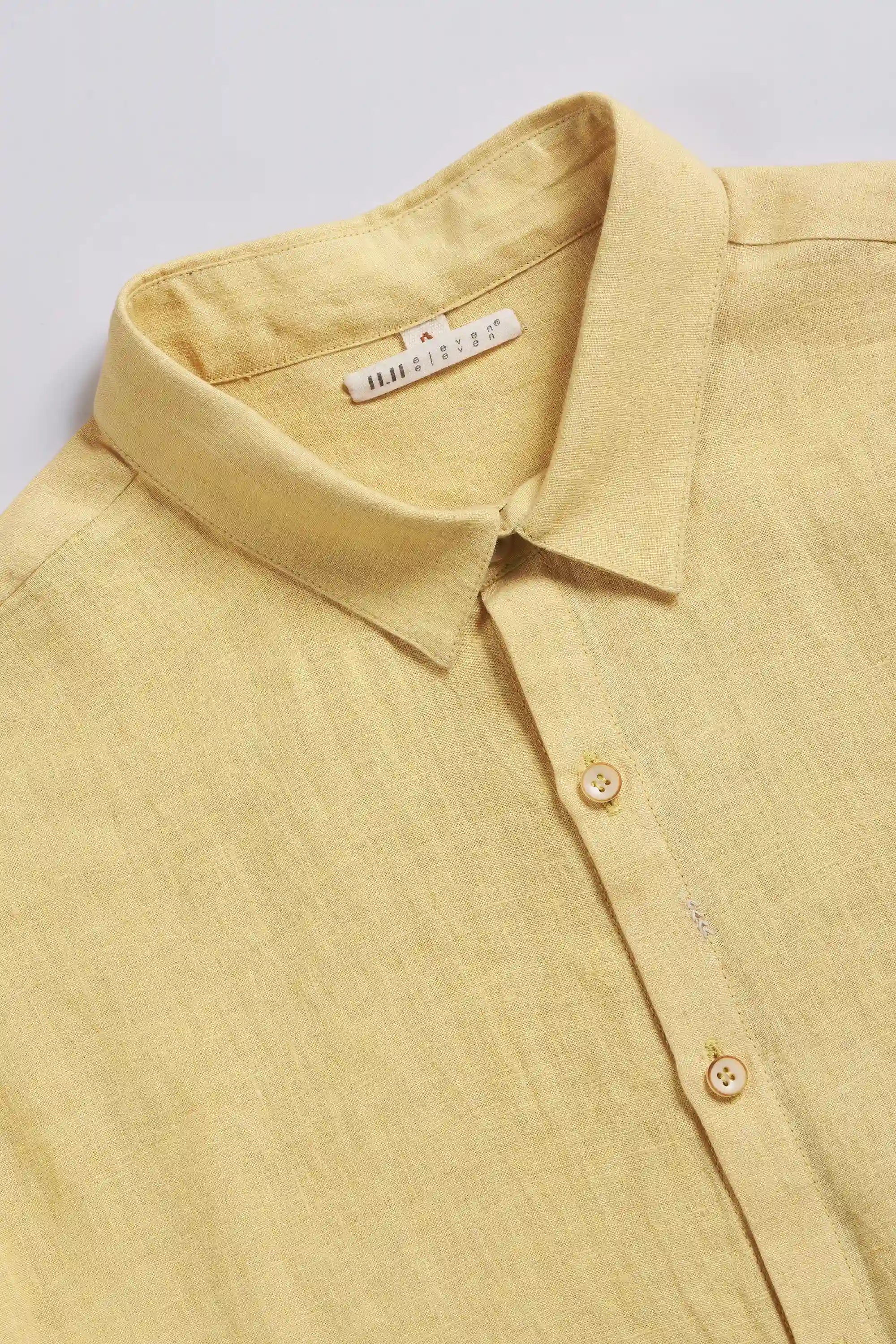 Close-up of a yellow shirt with a collar and buttons on a light grey background